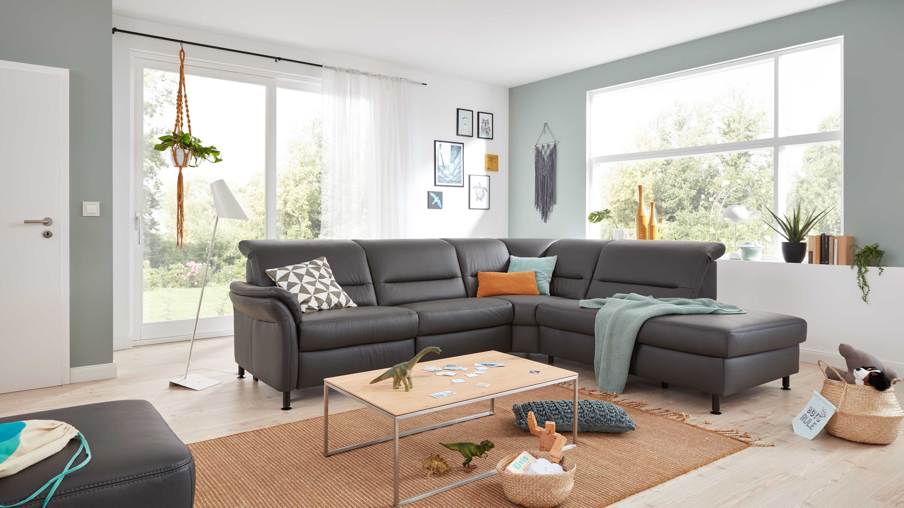 Anthrazitfarbenes Ecksofa mit verstellbaren Kopfstützen und schwarzen Füßen in modernem Wohnzimmer