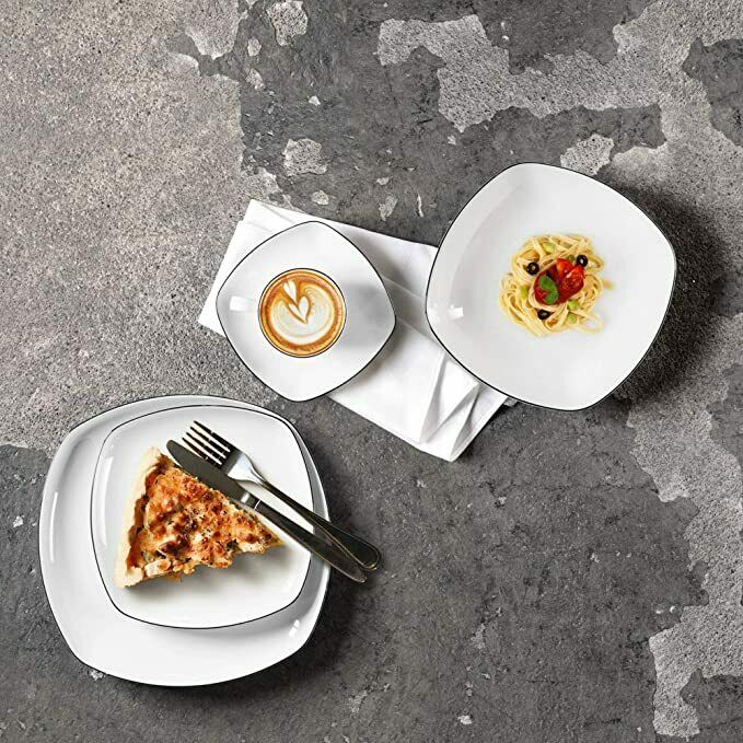 Pizza, Kaffee mit Latte Art und Salat in weißen Tellern, von oben auf grauer strukturierter Fläche arrangiert.