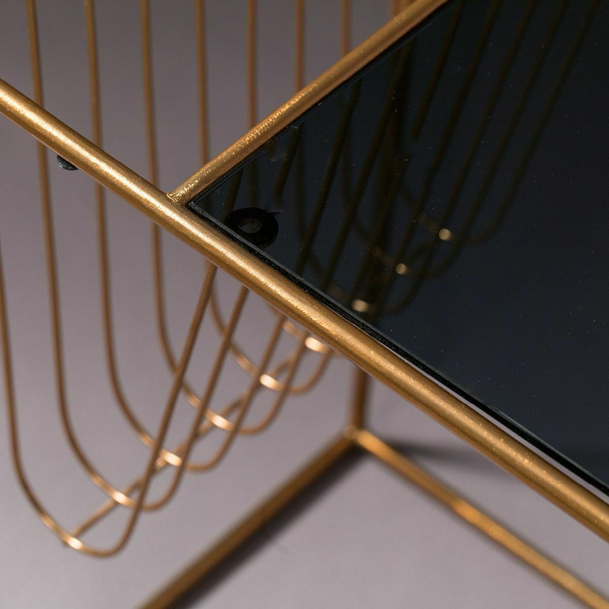Moderner Tisch aus Glas und goldfarbenem Metall Nahaufnahme eines modernen Tisches mit Glasplatte und goldfarbenem Metallgestell in geometrischem Design