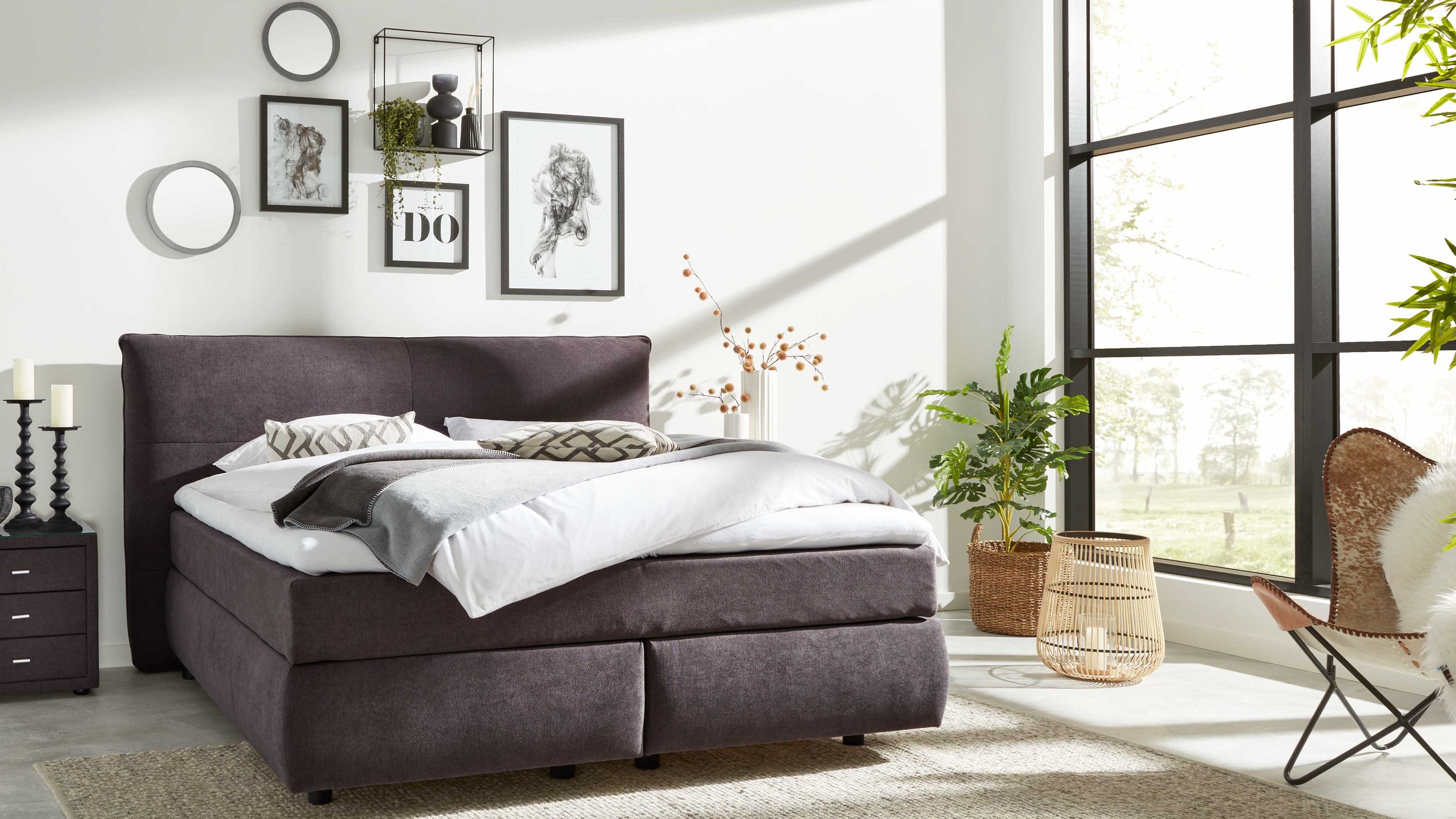 Boxspringbett mit dunkelgrauem Stoffbezug und gepolstertem Kopfteil in modernem Schlafzimmer