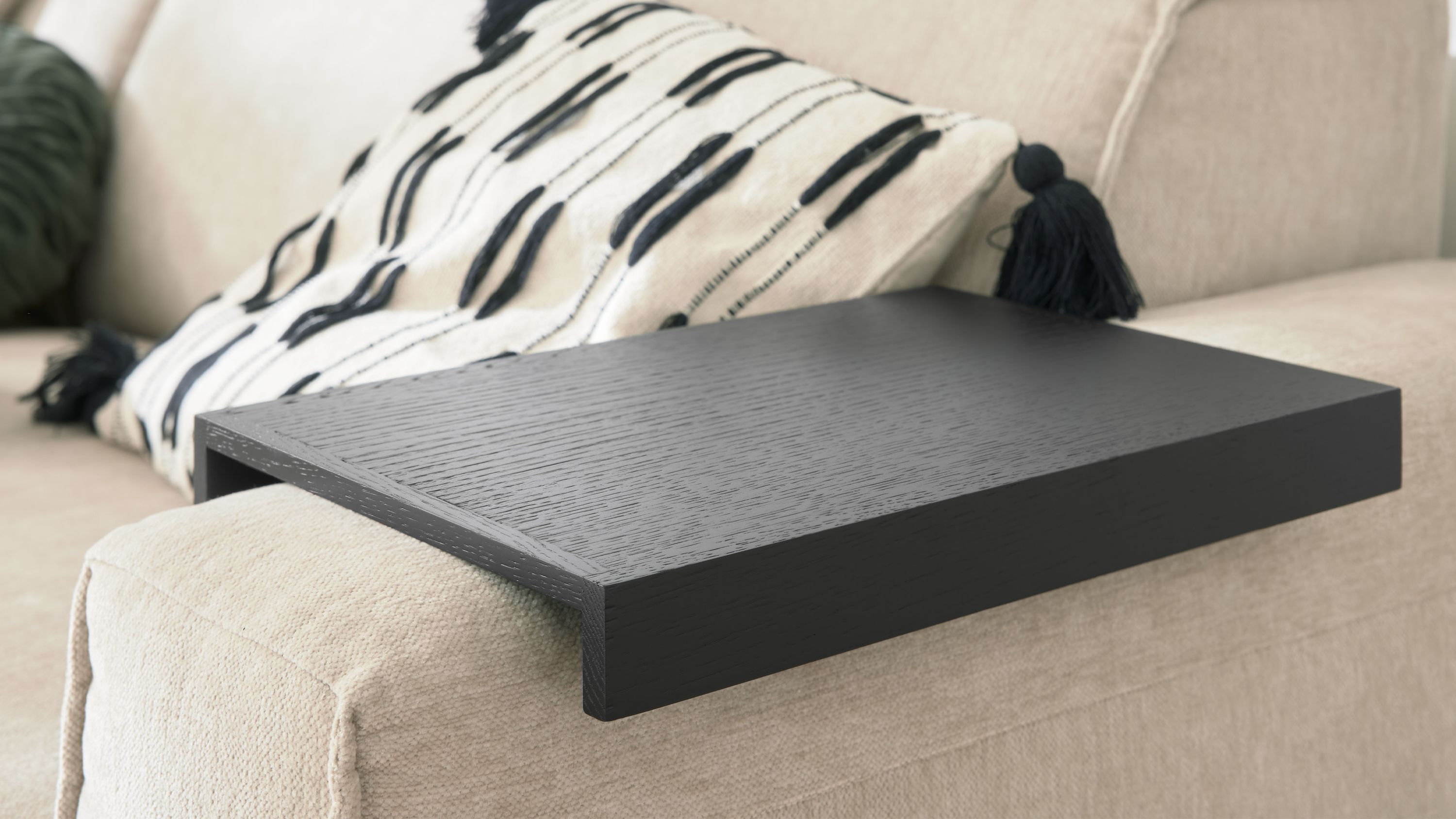 Schwarzes rechteckiges Armlehntablett aus Holz auf einem hellen Sofa
