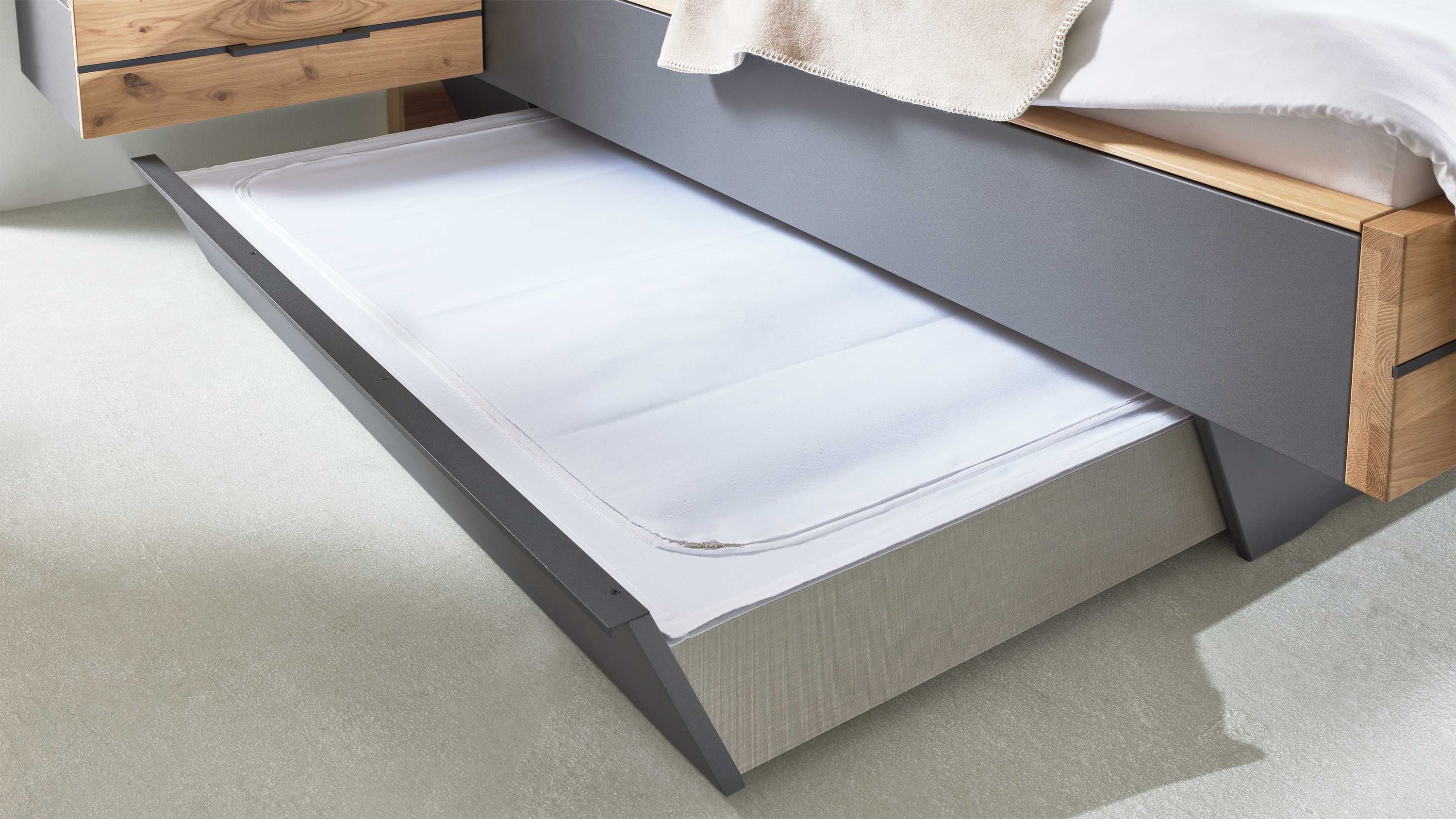 Zweiteiliges beige Abdeckungs-Set für Bettschubladen unter einem grauen Bett mit Holzakzenten