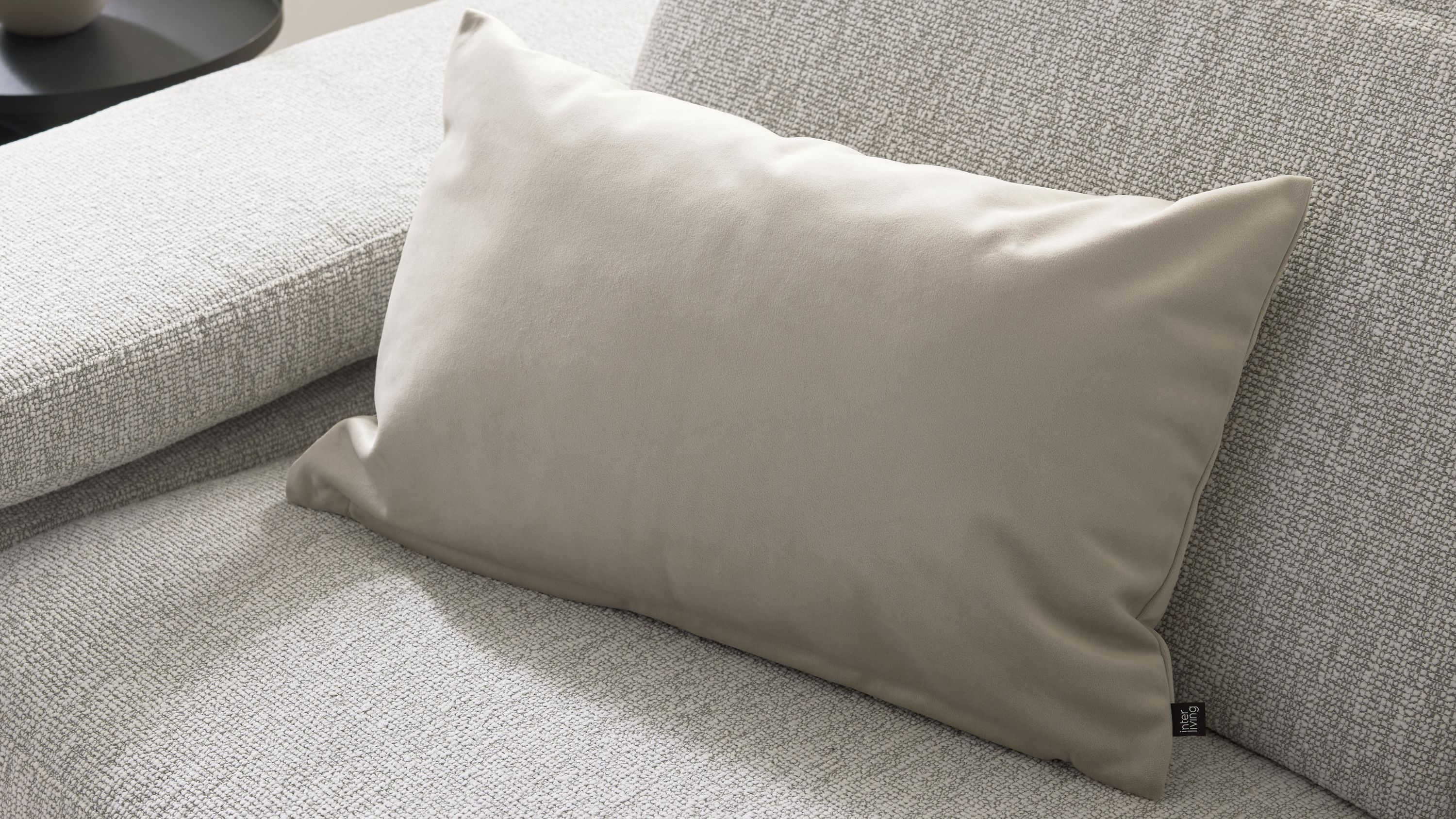 Rechteckige naturfarbene Kissenhülle auf hellgrauem Sofa