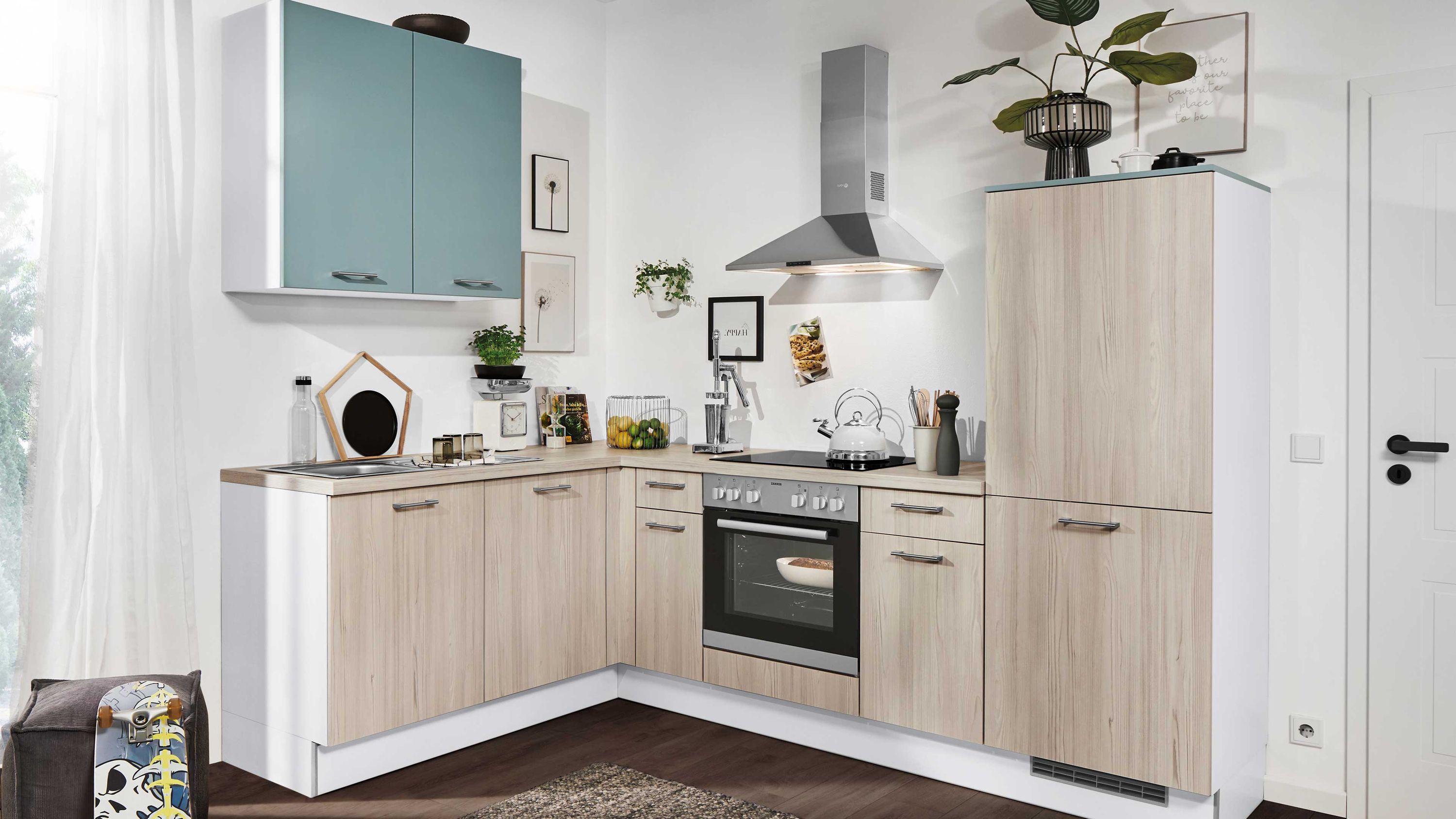 Eckküche in Holzoptik mit türkisfarbenen Akzenten. Helle Eckküche mit Holzoptik-Fronten türkisfarbenen Hängeschränken und Edelstahlhaube.