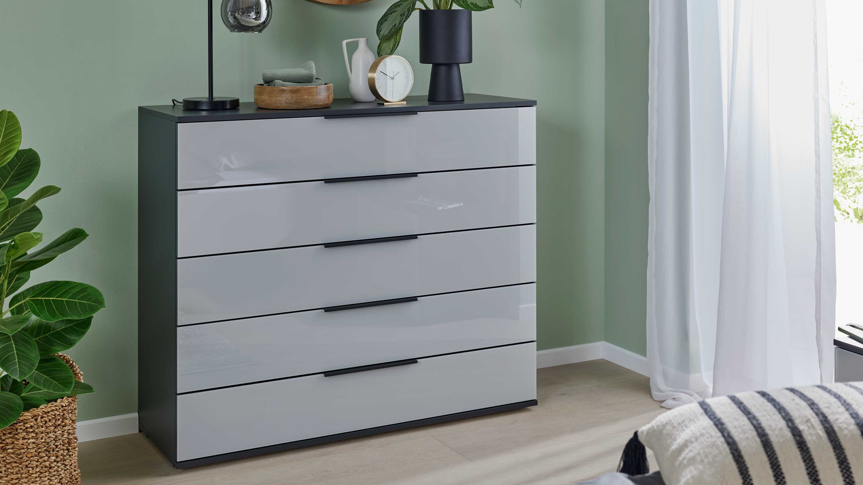 Schubladenkommode mit fünf Schubladen in zwei Farben Schubladenkommode mit fünf Schubladen in seidengrau und basaltfarben im Schlafzimmer vor grüner Wand
