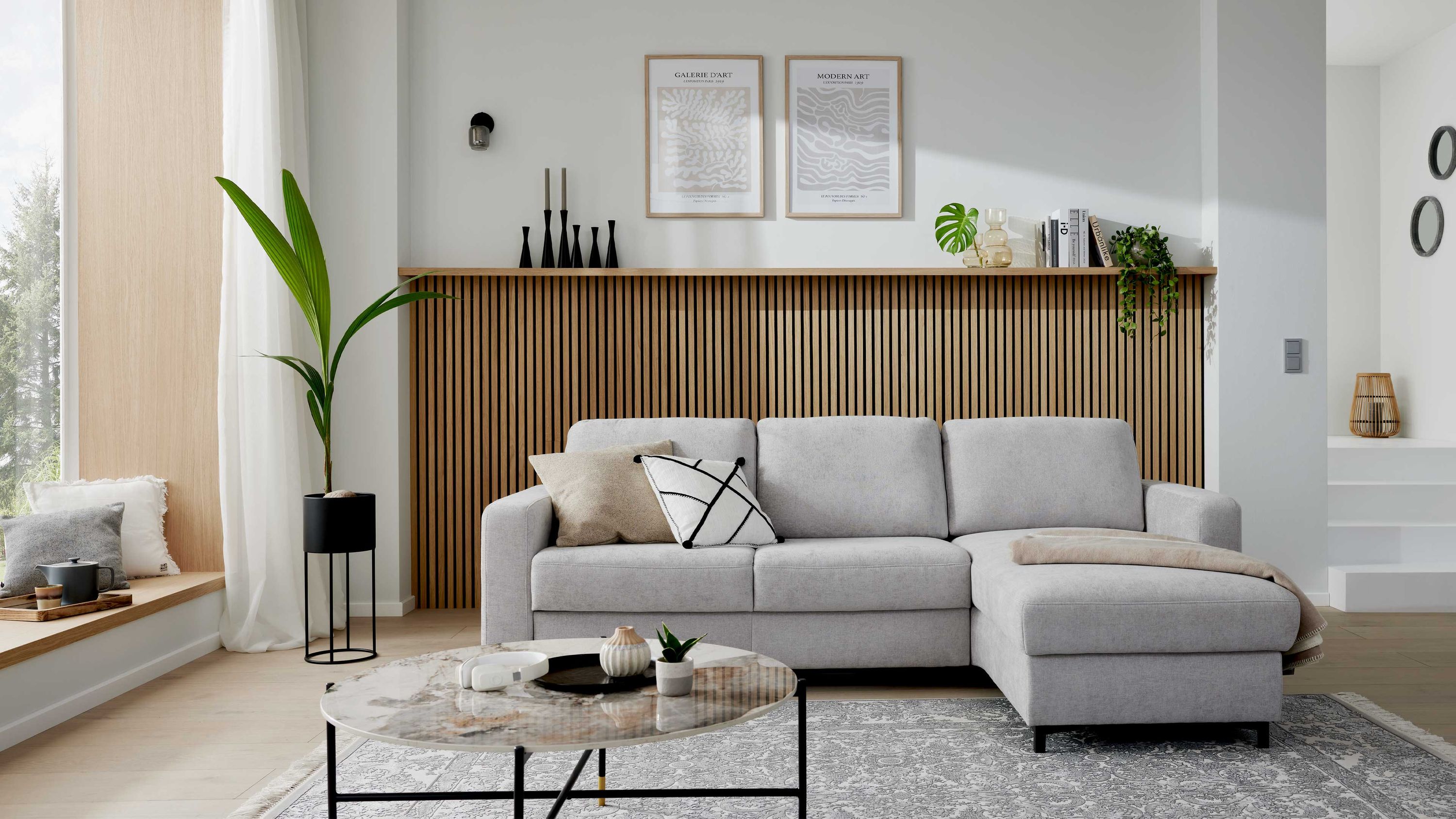 Ecksofa mit silberfarbenem Bezug und schwarzen Metallfüßen in modernem Wohnzimmer