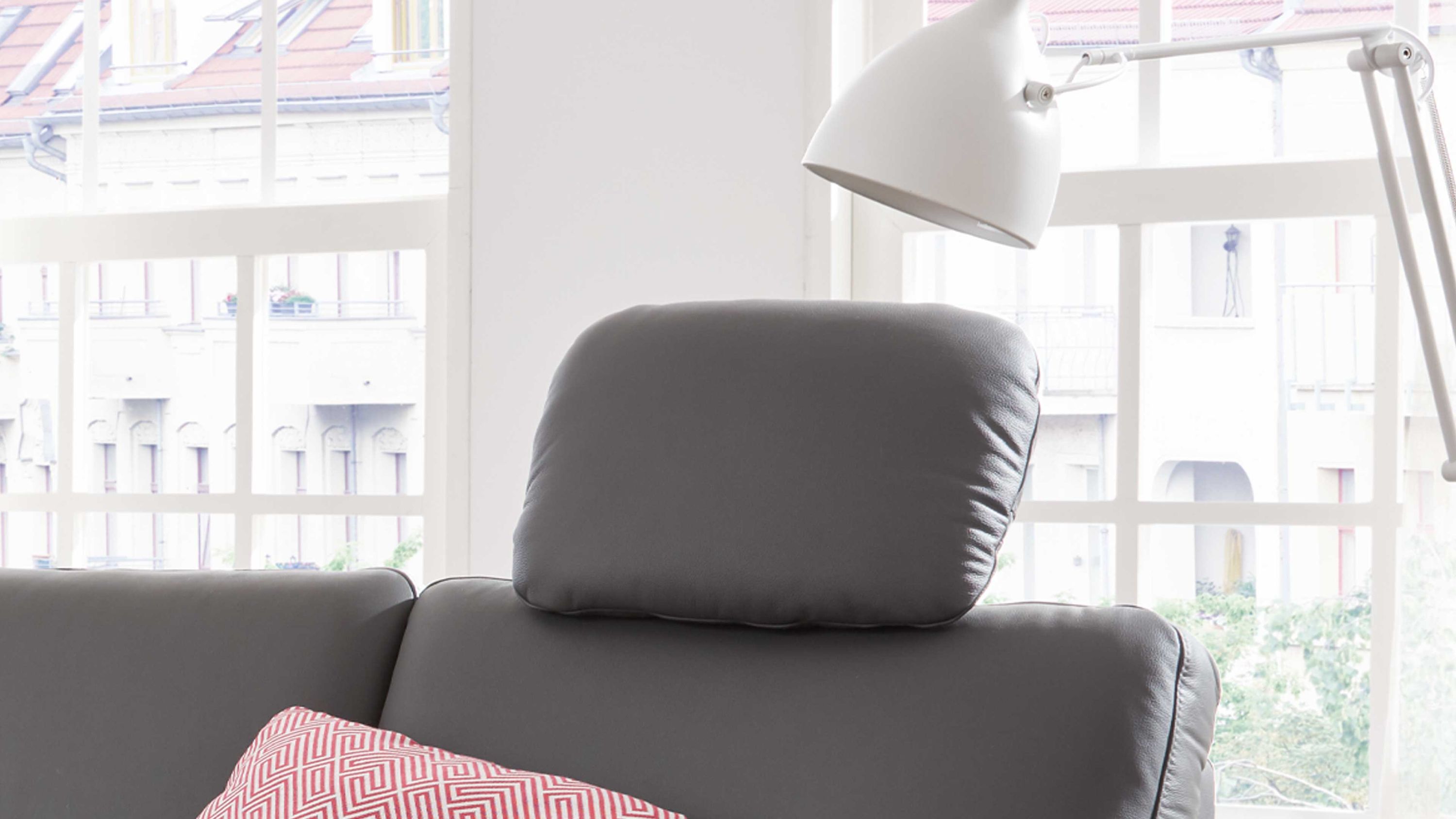Kopfstütze in Anthrazit auf Sofa Anthrazitfarbene Kopfstütze mit abgerundeter Form auf grauem Sofa vor Fenster