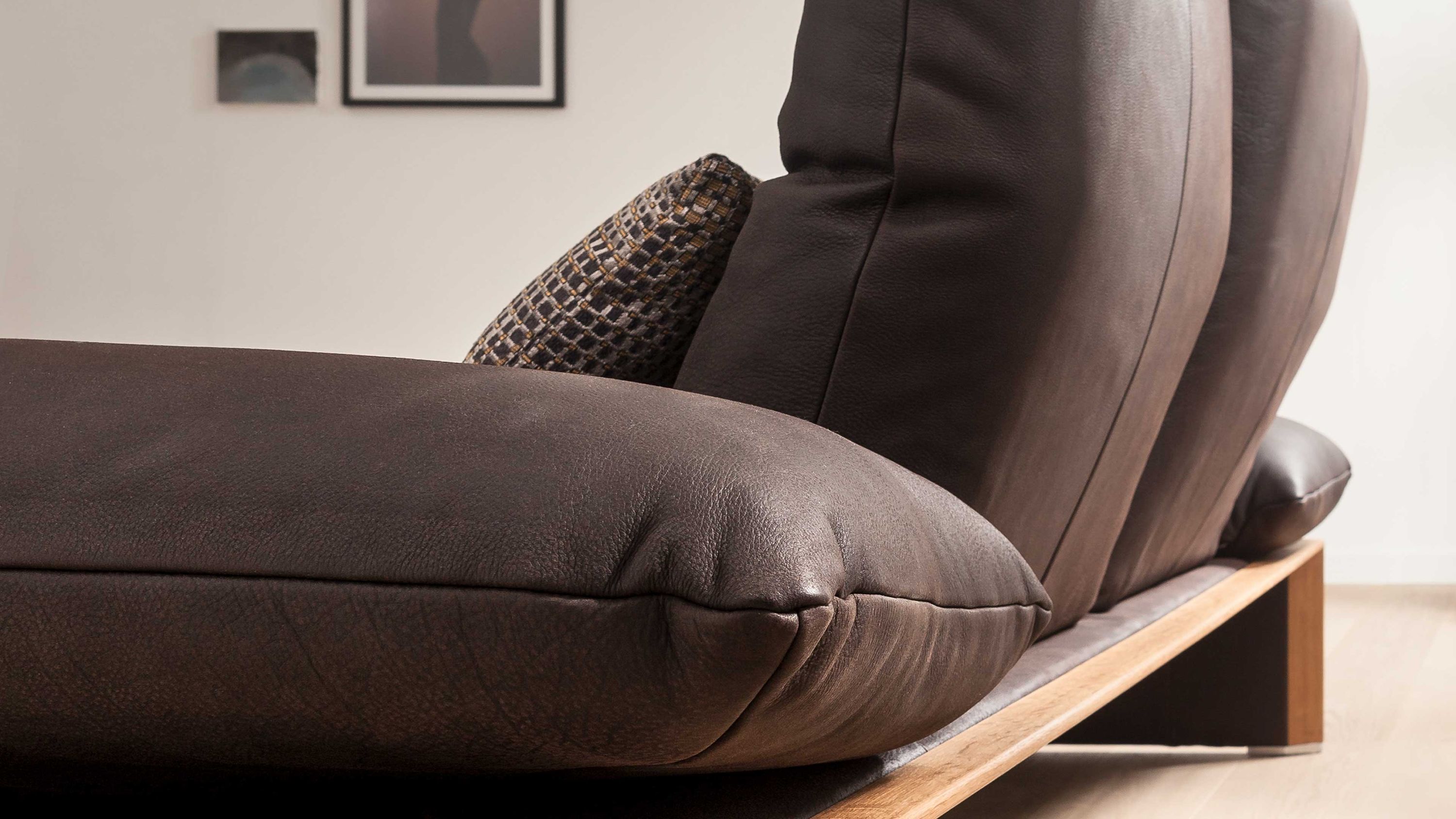 Zweisitzer Ledersofa mit Holzgestell und Kissen Zweisitziges Sofa mit braunem Lederbezug und Holzgestell Kissen mit Muster