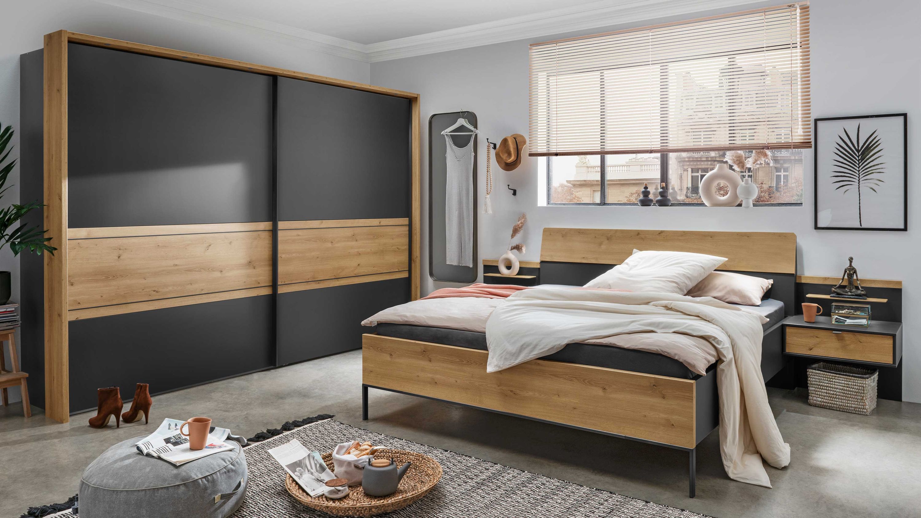 Schlafzimmer mit Bett Nachttisch und großem Schwebetürenschrank in Holz- und graphitfarbenen Flächen