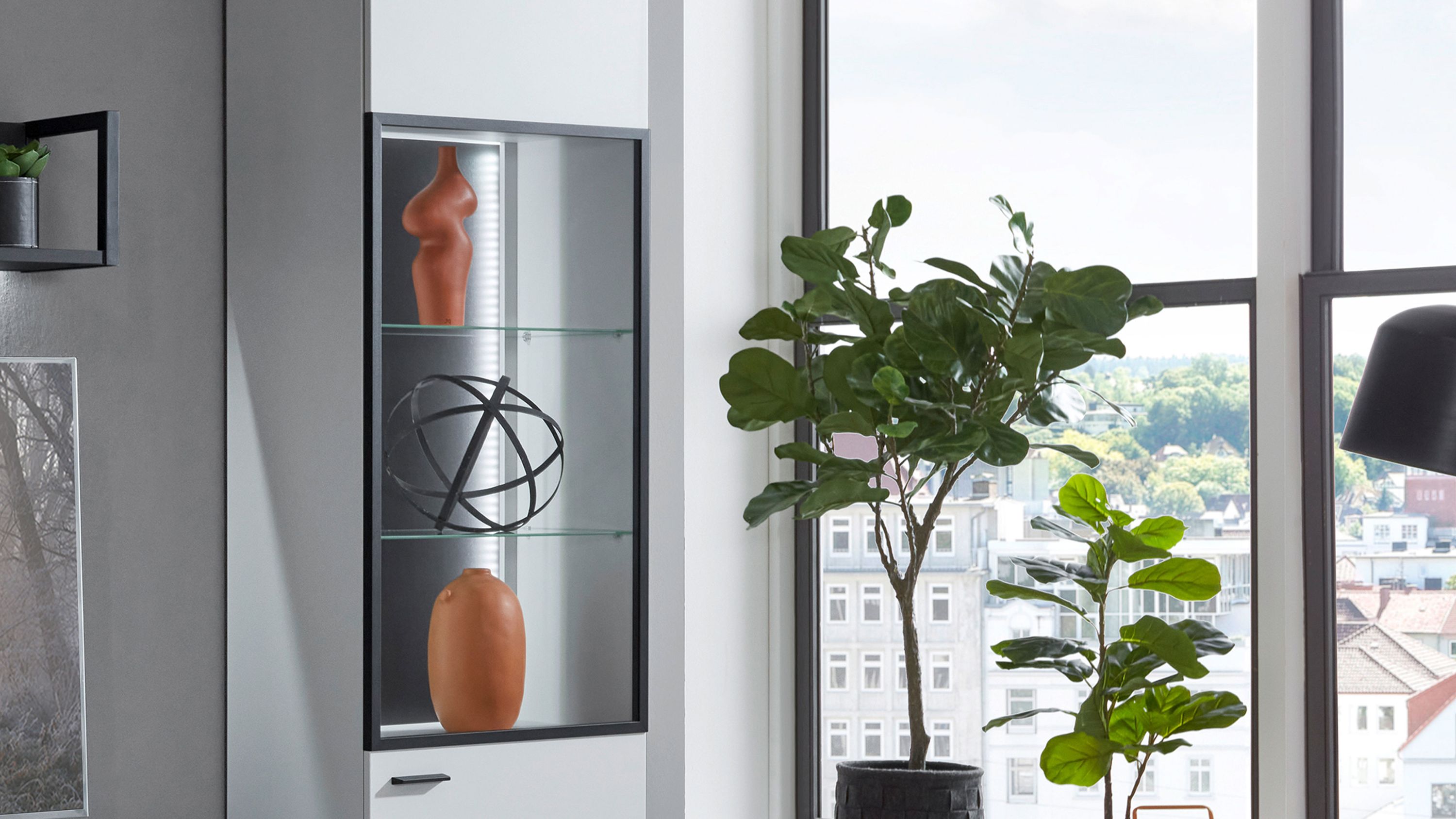 Schwarze Vitrine mit Glasfront und drei Glasböden LED-Beleuchtung innen dekorative Objekte darin