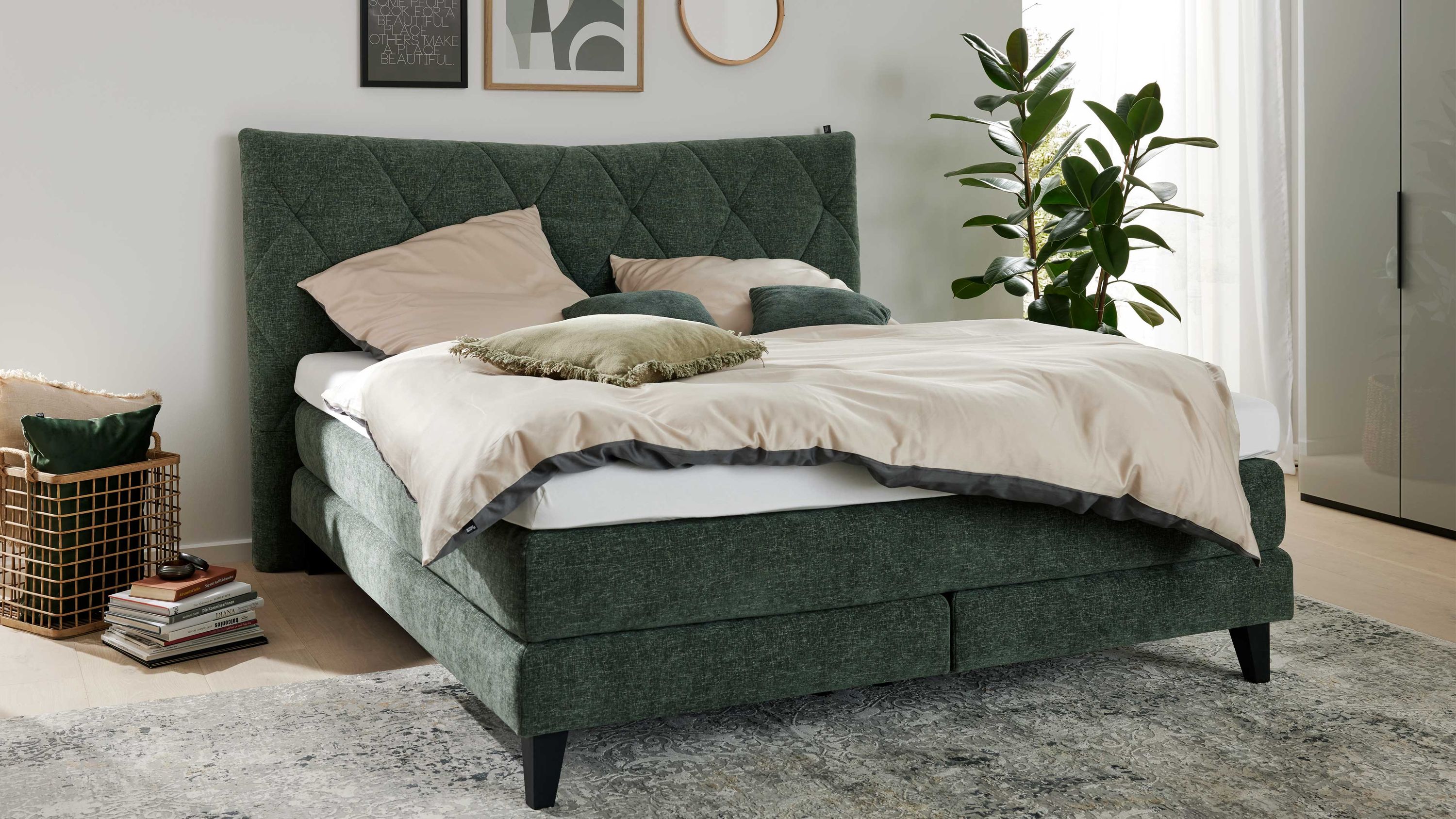 Boxspringbett mit moosgrünem Stoff und schwarzer Holzfüßen Boxspringbett mit gepolstertem Kopfteil in moosgrün und schwarzen Holzfüßen mit heller Bettwäsche