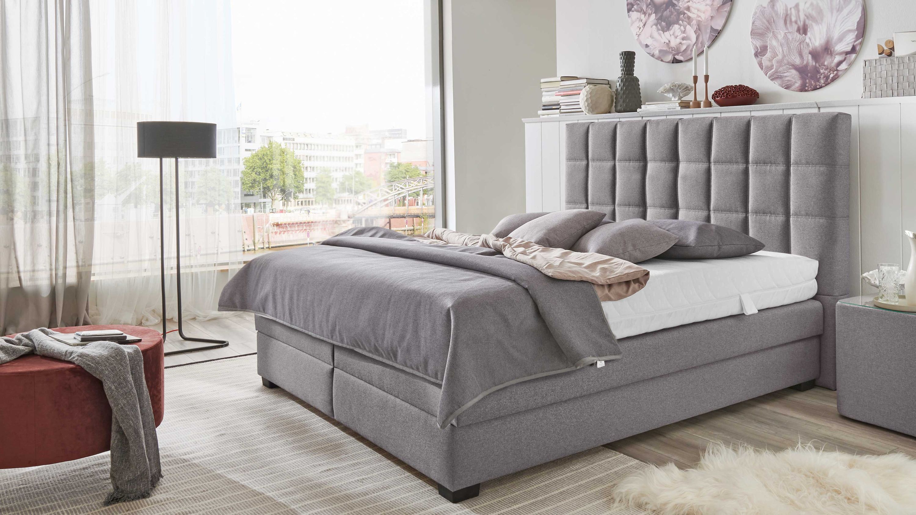 Boxspringbett mit Bettkasten und silbergrauem Bezug Boxspringbett mit gepolstertem Kopfteil und silbergrauem Bezug in modernem Schlafzimmer