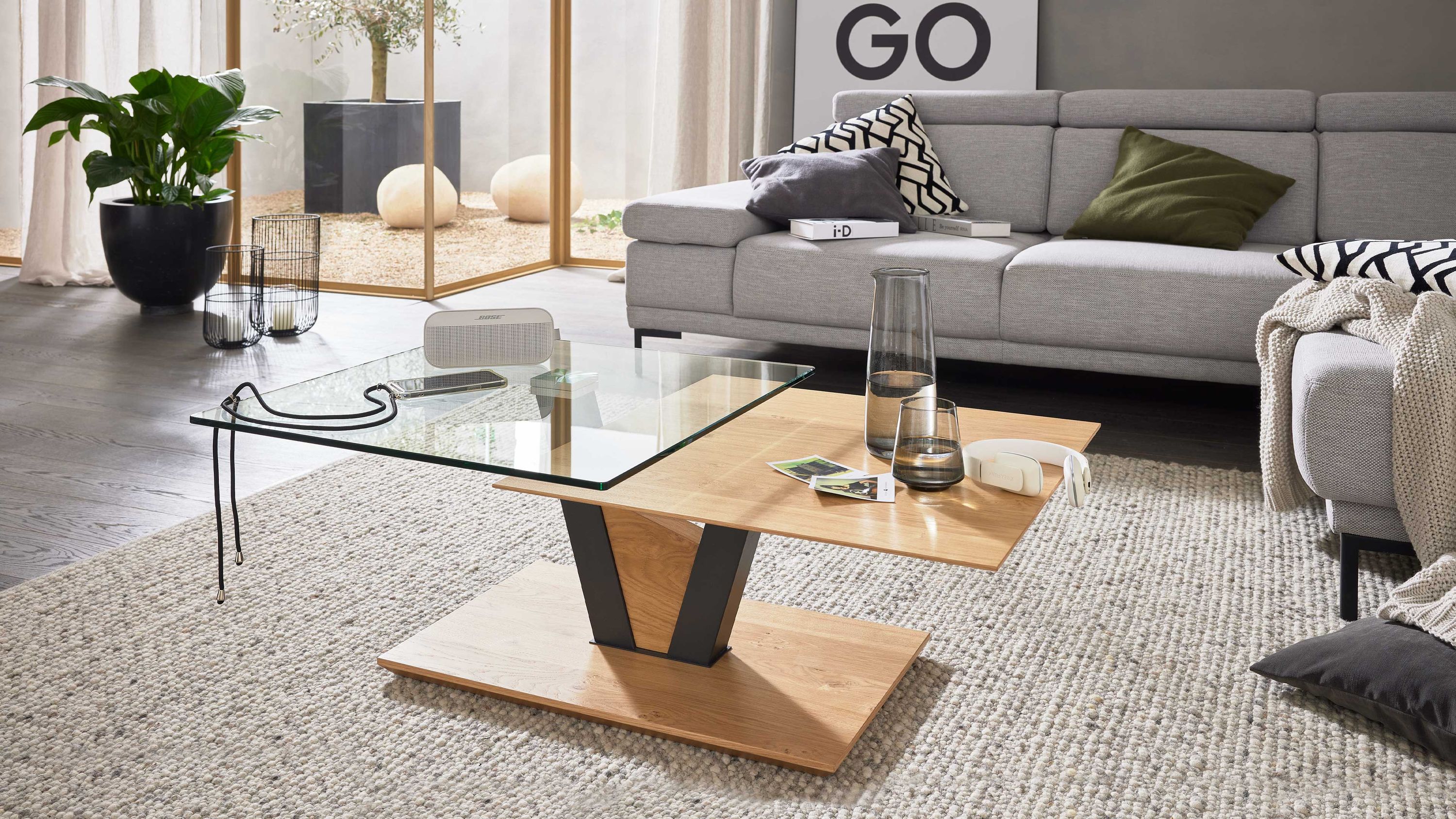 Quadratischer Couchtisch mit Glas- und Holzplatte in Eichenoptik auf Holzsockel mit schwarzem Metallgestell
