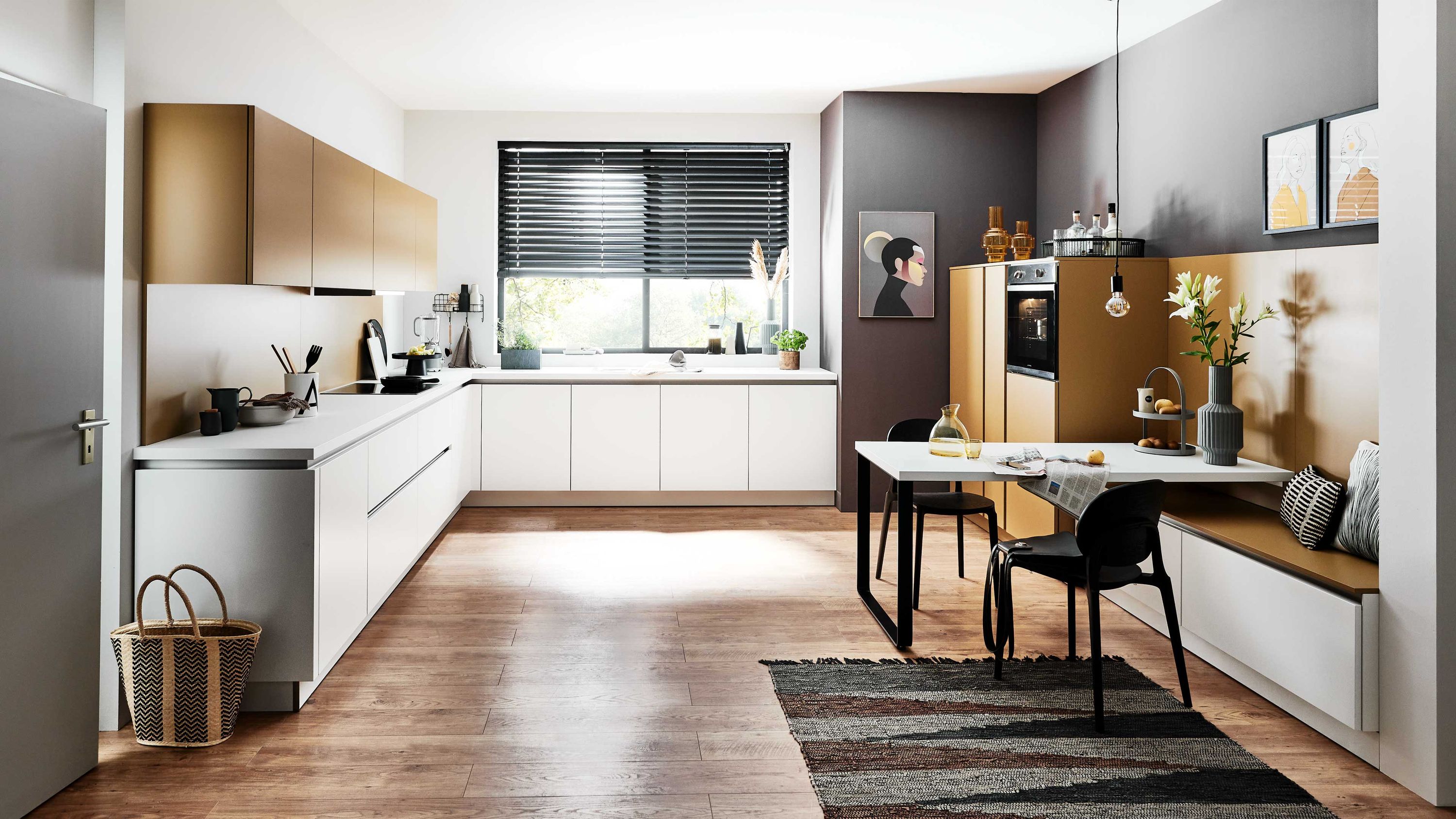 Moderne Wohnküche mit Sitzbanklösung Naturmaterialien und klarer Linienführung Küche mit Holz-weiß-Fronten Fenster mit schwarzen Jalousien Sitzbank Holzboden Teppich Esstisch mittig