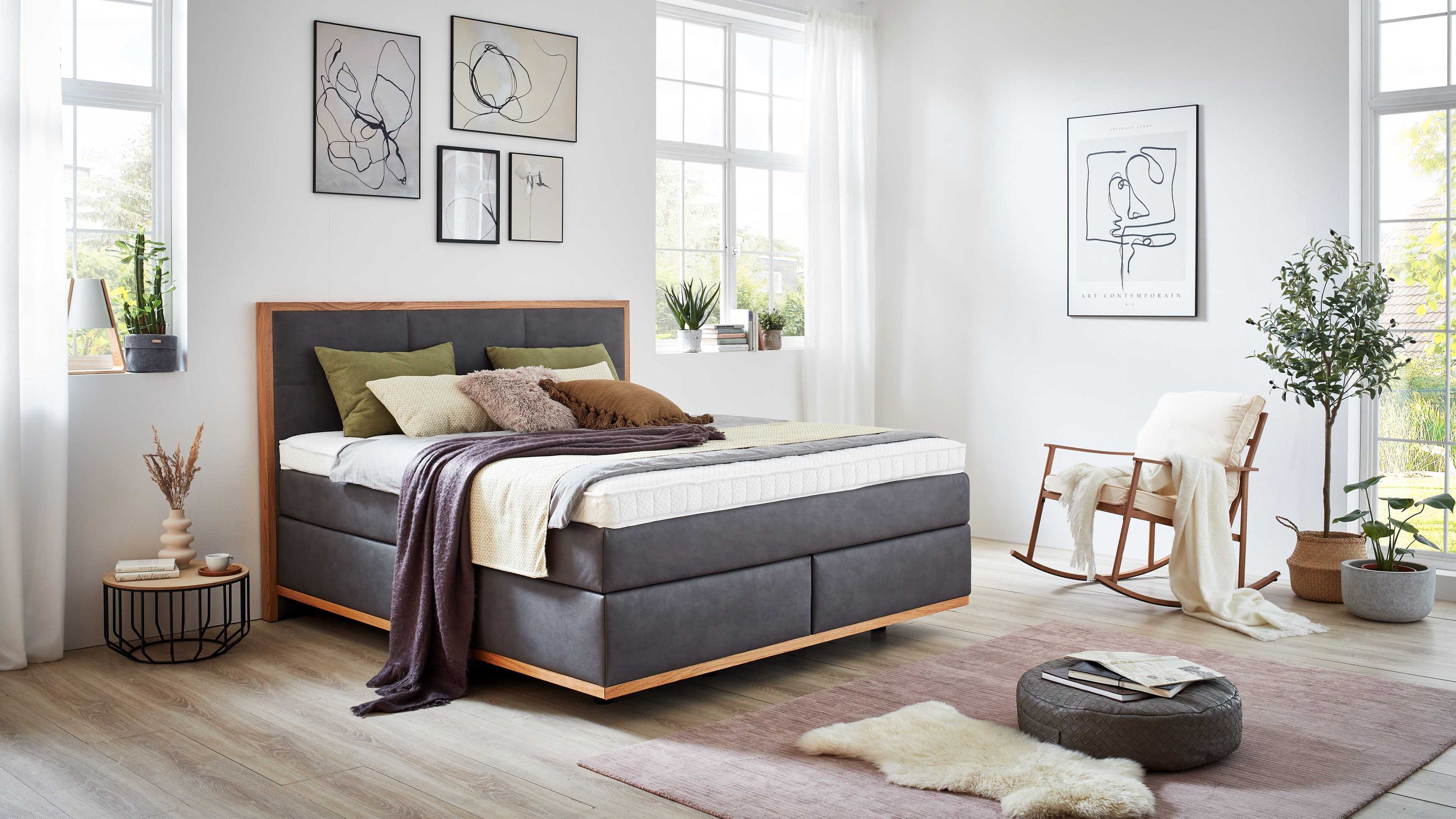Boxspringbett mit steinfarbenem Bezug und Holzrahmen im Kopf- und Fußteil in modernem Schlafzimmer