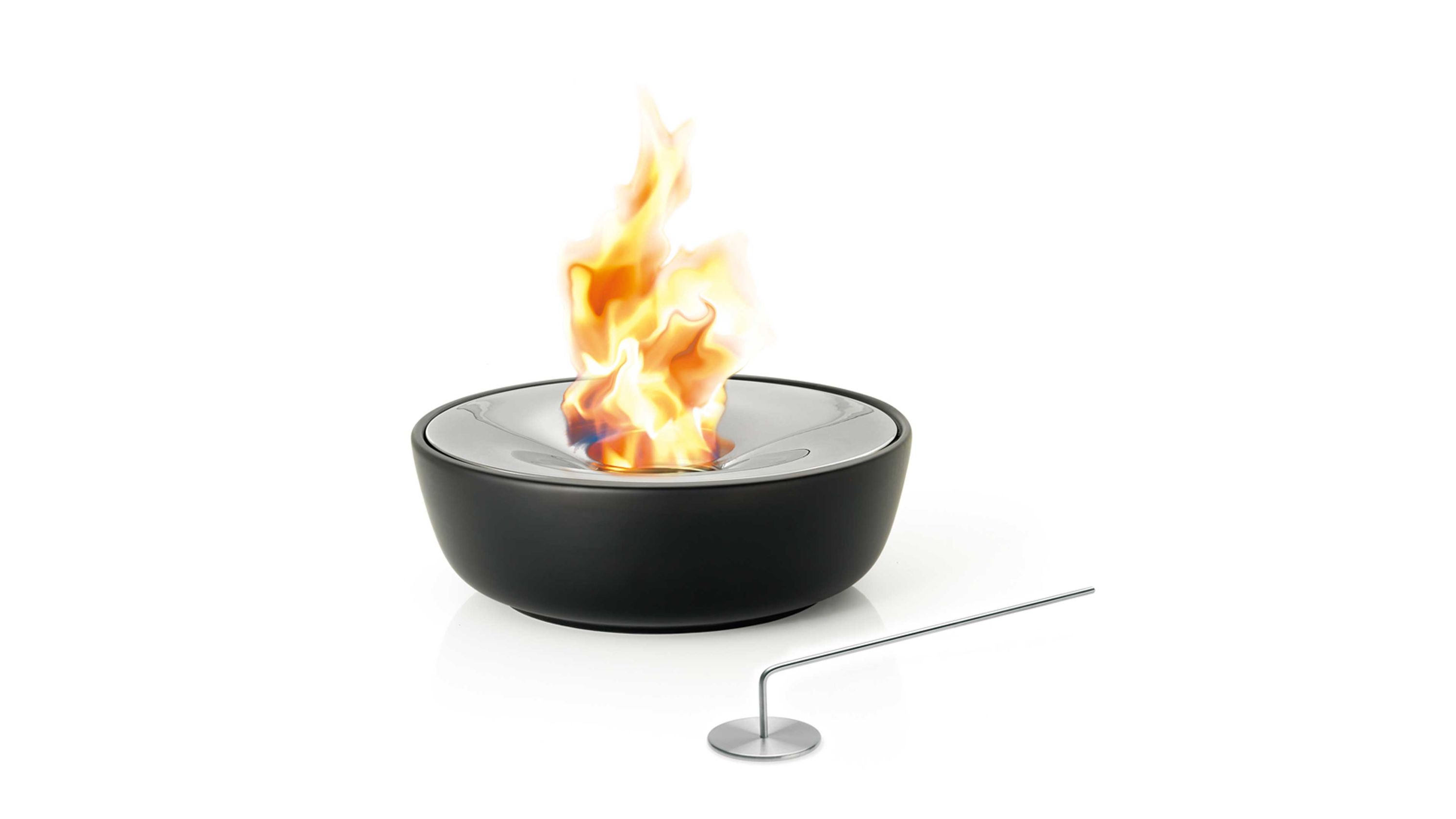 Runde schwarze Feuerstelle aus Keramik mit poliertem Edelstahlrand und brennender Flamme