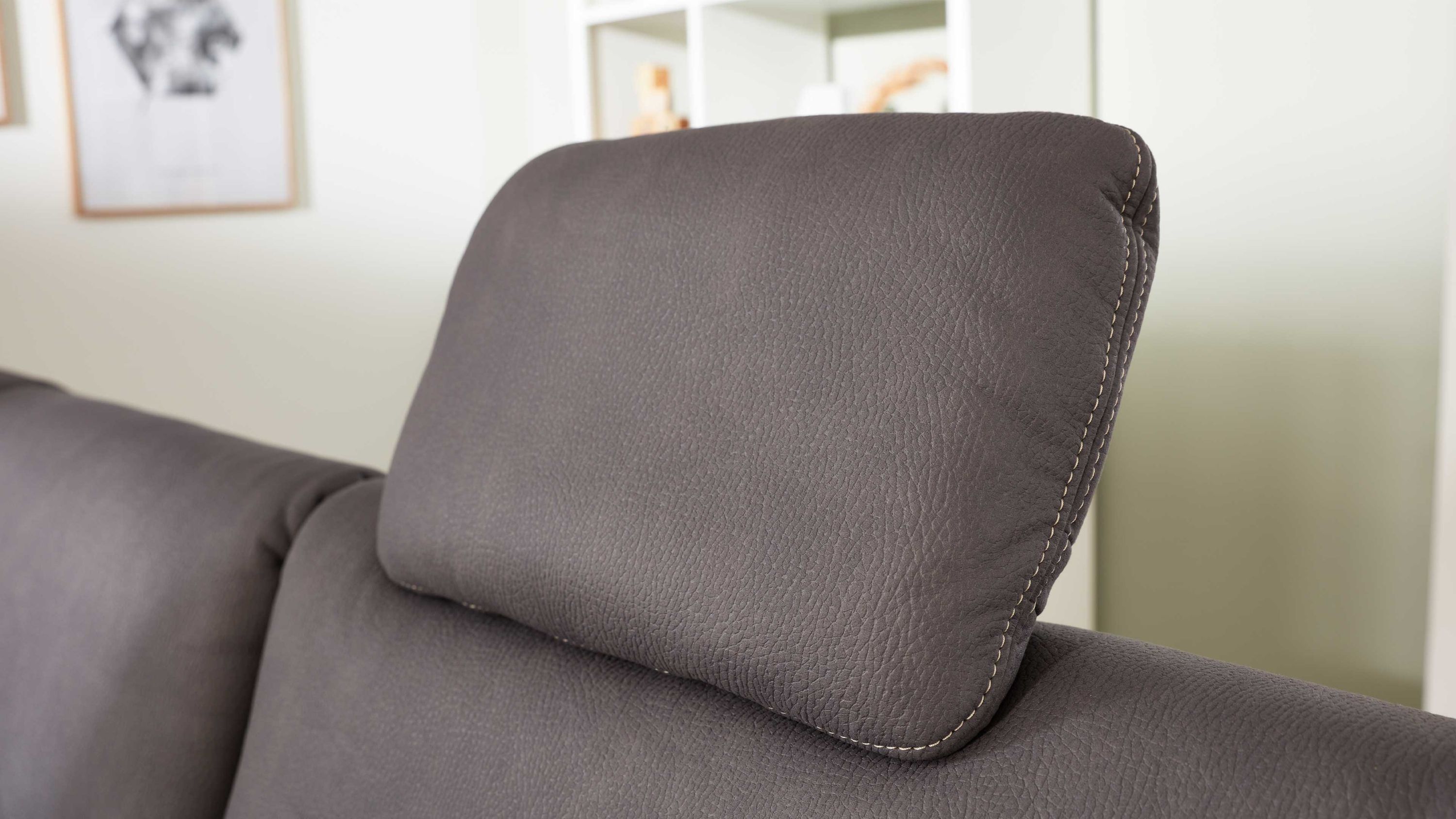 Graue rechteckige Kopfstütze mit abgerundeten Ecken auf einem grauen Sofa