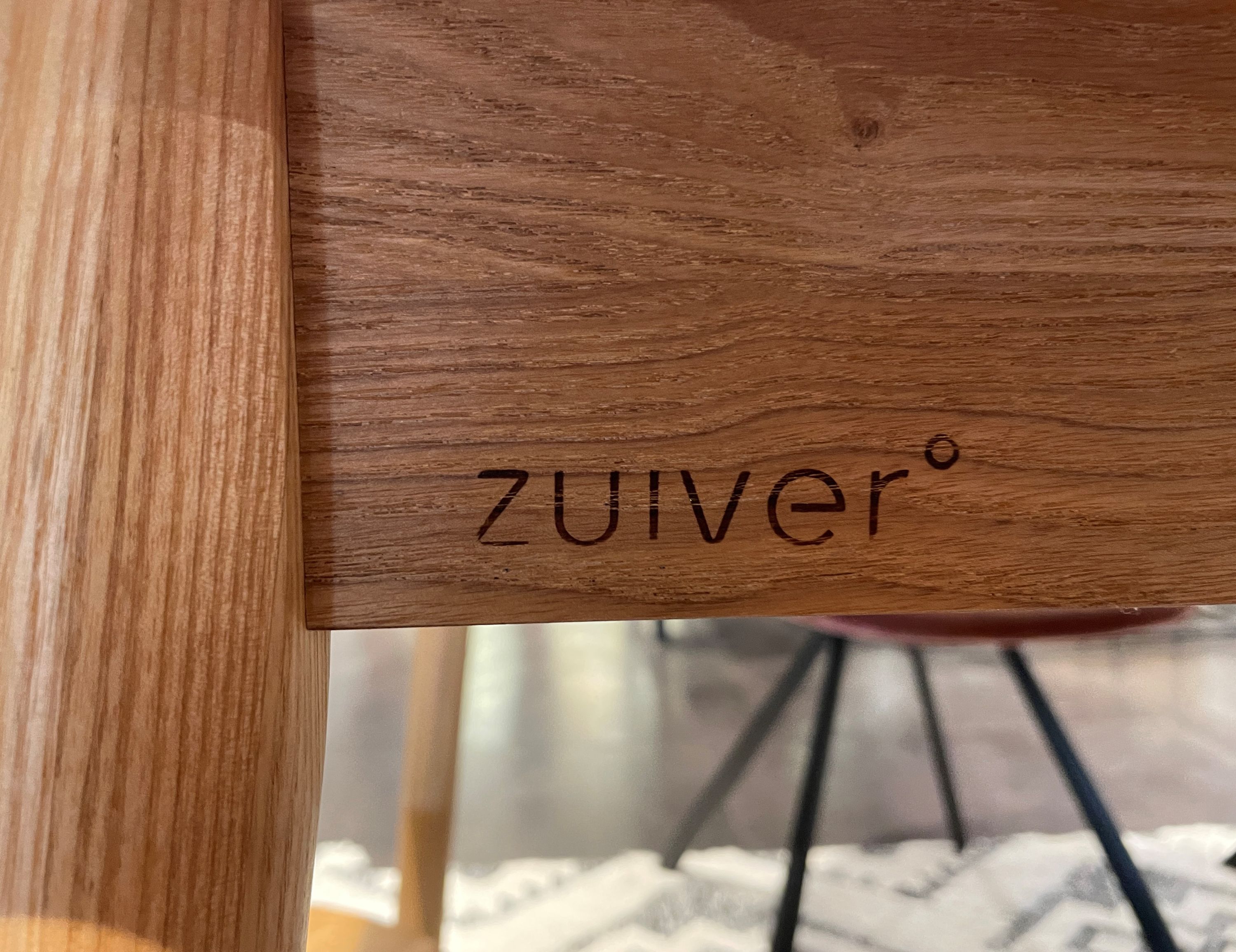 Nahaufnahme des eingravierten Zuiver-Logos auf einer hellbraunen Holzoberfläche.