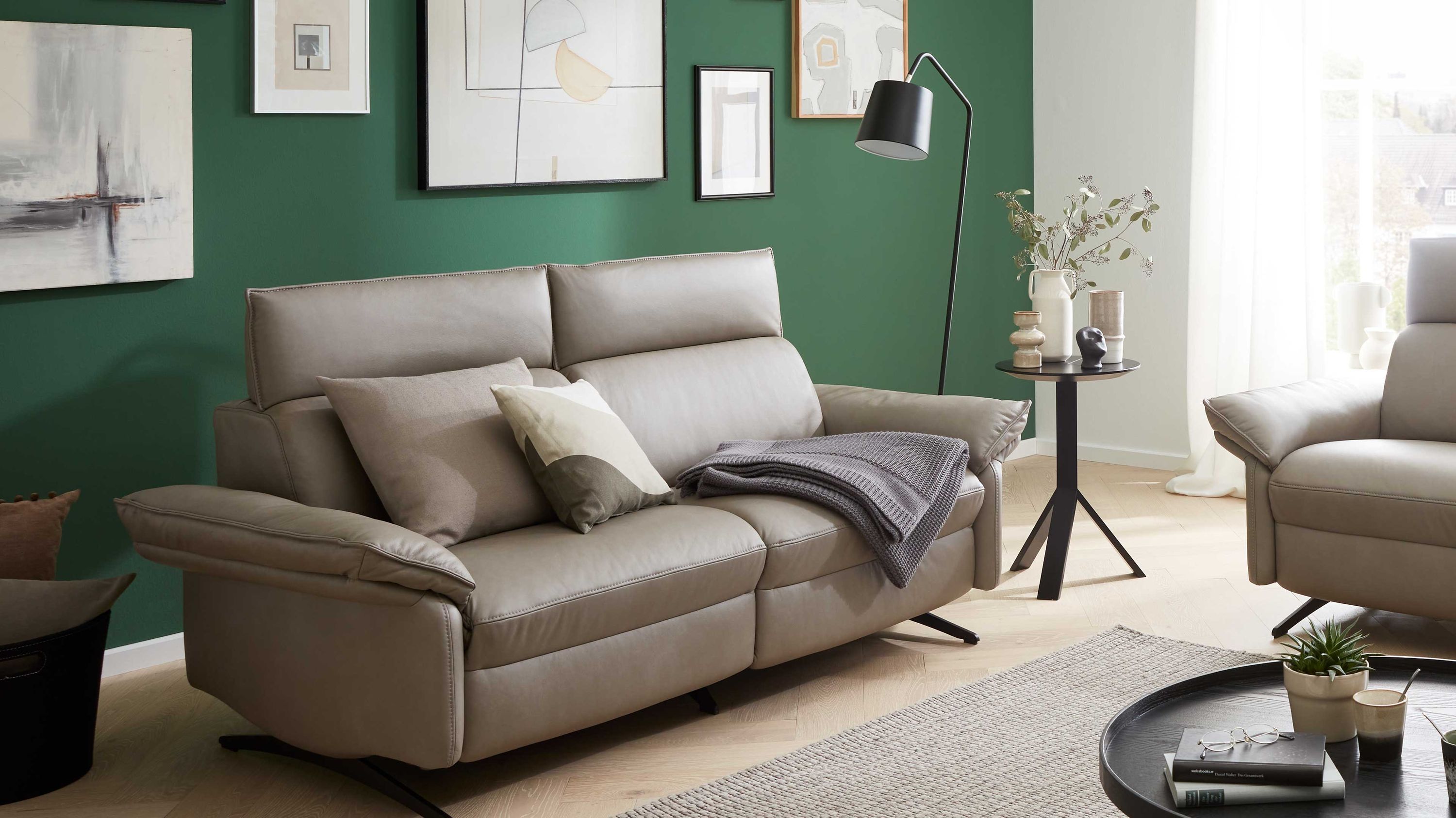 Dreisitziges Sofa in graubeiger Farbe mit gepolsterten Armlehnen und Rückenlehnen in modernem Wohnzimmer