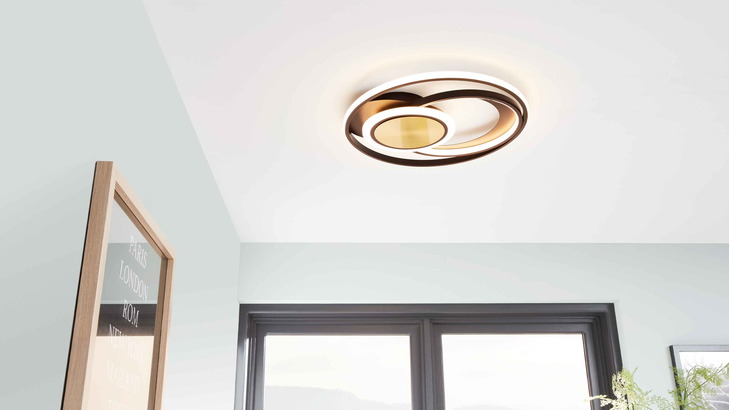 Runde Deckenleuchte mit schwarzen und messingfarbenen Ringen an weißer Decke