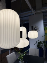 Stilvolle, moderne Deckenlampe in hellem Design, die über einem Esszimmertisch hängt und für angenehmes Licht sorgt.