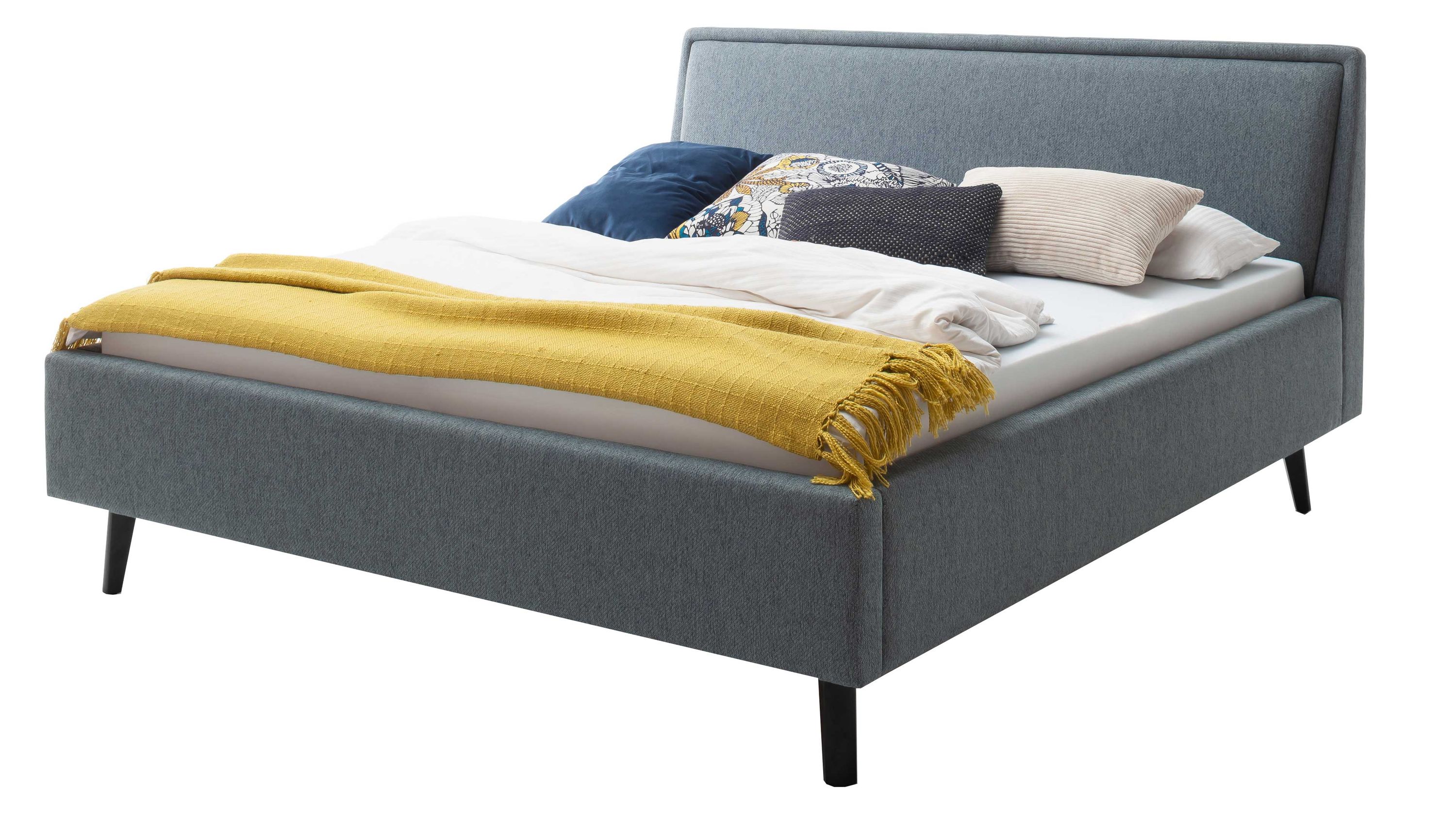 Polsterbett mit oceanfarbenem Bezug und schwarzen Holzfüßen Polsterbett mit rechteckigem Kopfteil oceanfarbener Bezug und schwarzen Holzfüßen mit Bettdecke und Kissen belegt