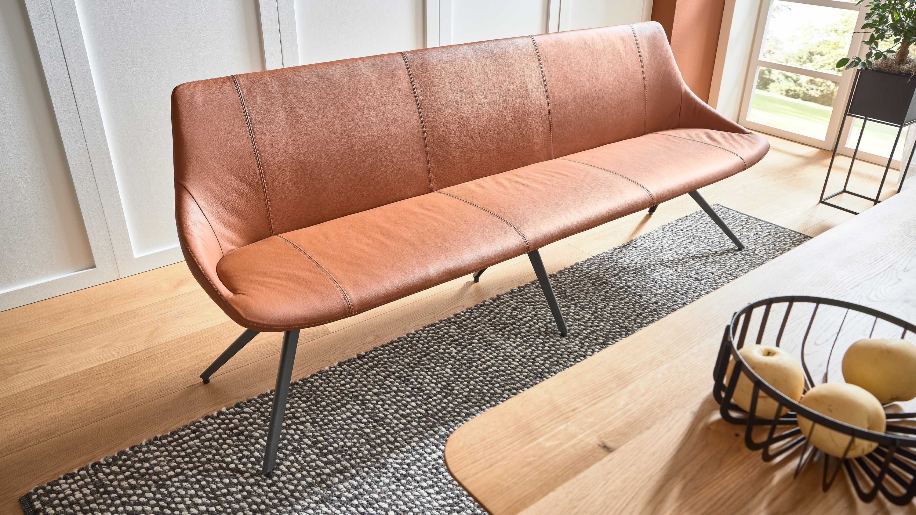 Polsterbank mit sattelfarbenem Bezug und anthrazitfarbenen Metallbeinen in einem Esszimmer