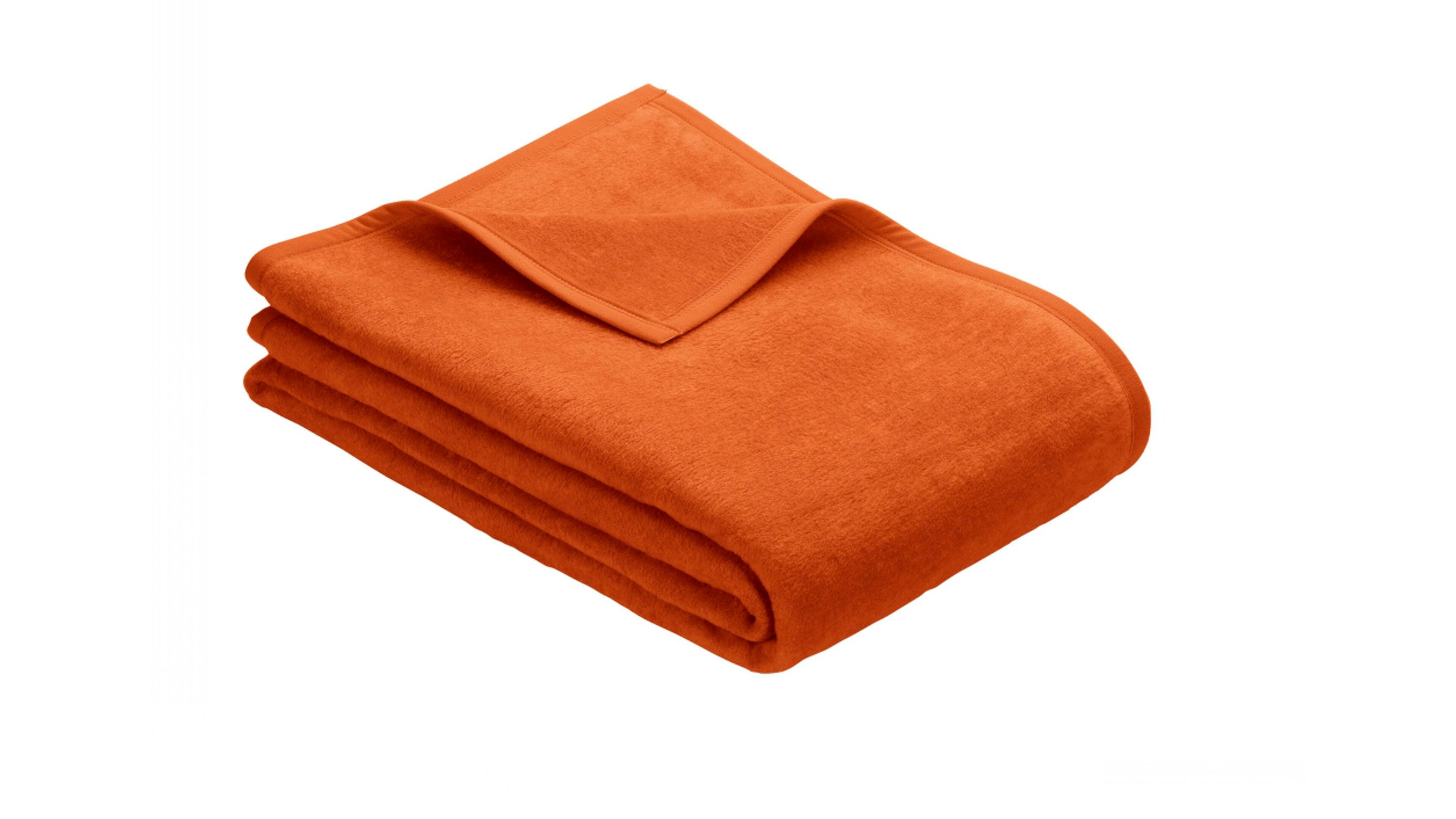 Gefaltete orangefarbene Fleecedecke mit sichtbarer Kante