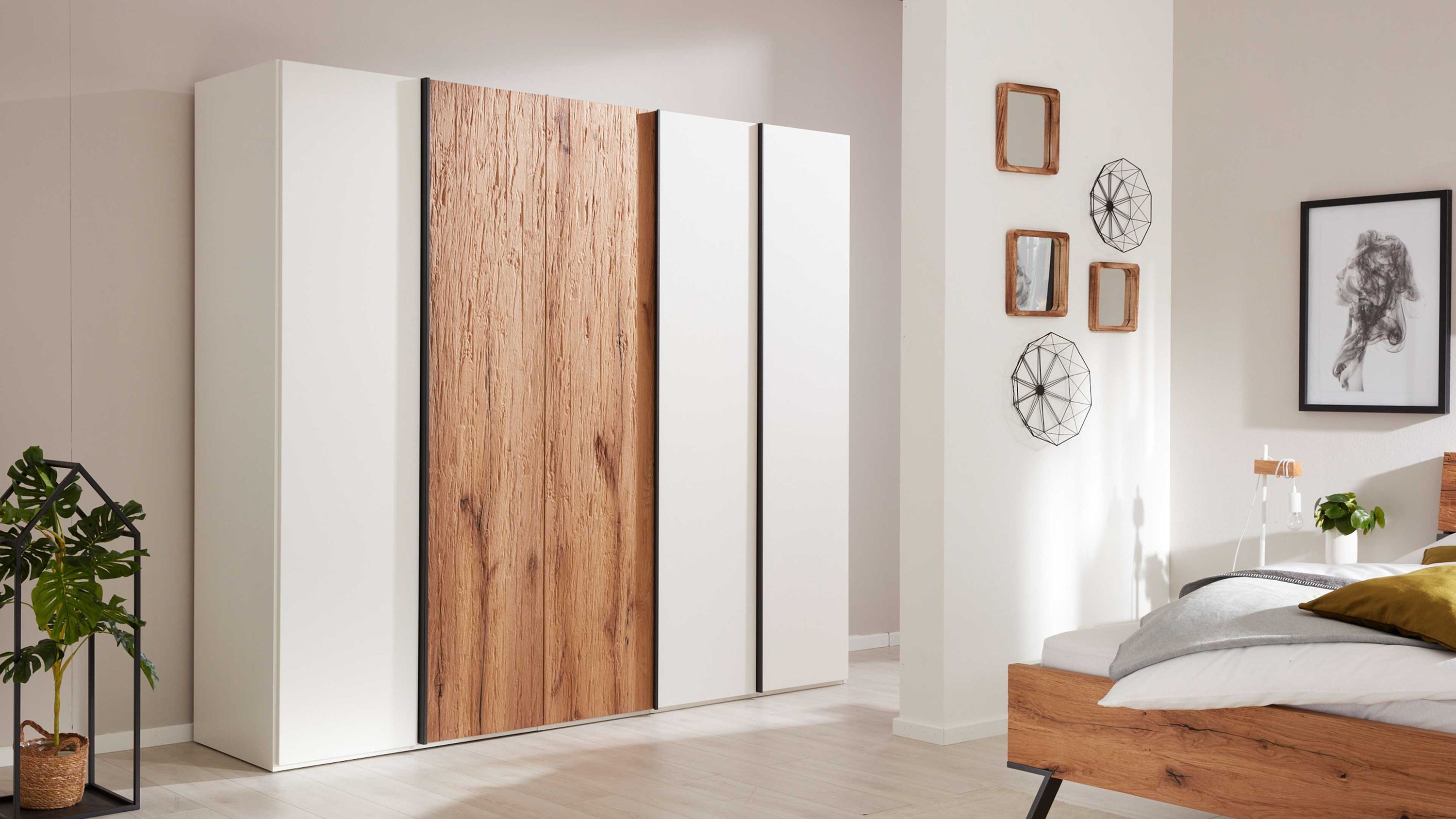 Fünftüriger Kleiderschrank mit weißen und holzfarbenen Türen in einem Schlafzimmer
