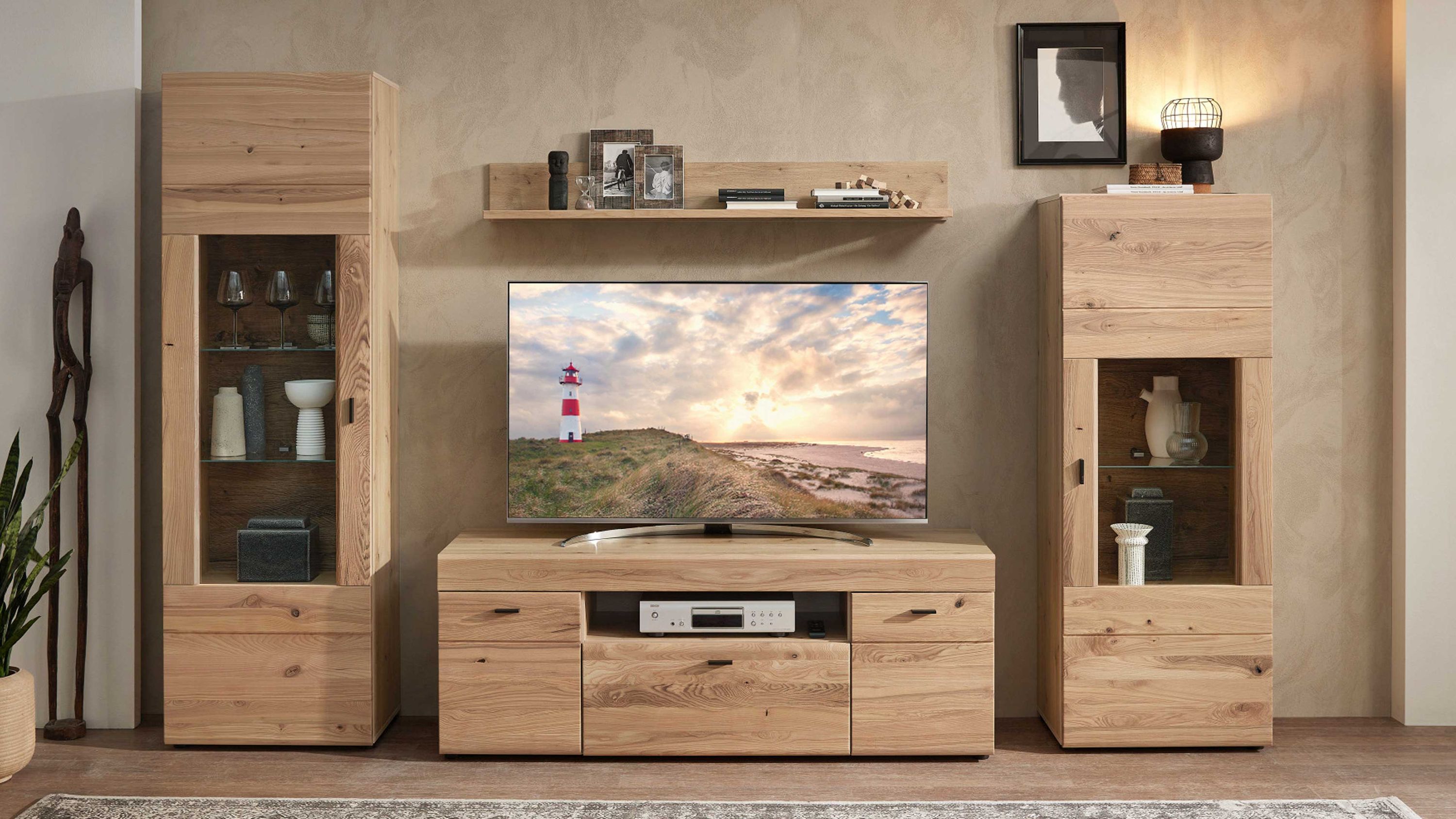Vierteilige Wohnwand aus hellem Holz mit Vitrinen und TV-Board Vierteilige Wohnwand aus hellem Holz mit zwei hohen Vitrinen einem TV-Board und einem Wandregal