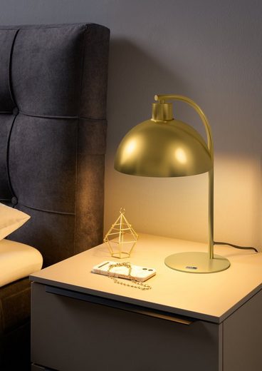 Nachttisch mit goldener Lampe, Smartphone und geometrischem Dekoobjekt, aus frontaler Perspektive fotografiert.