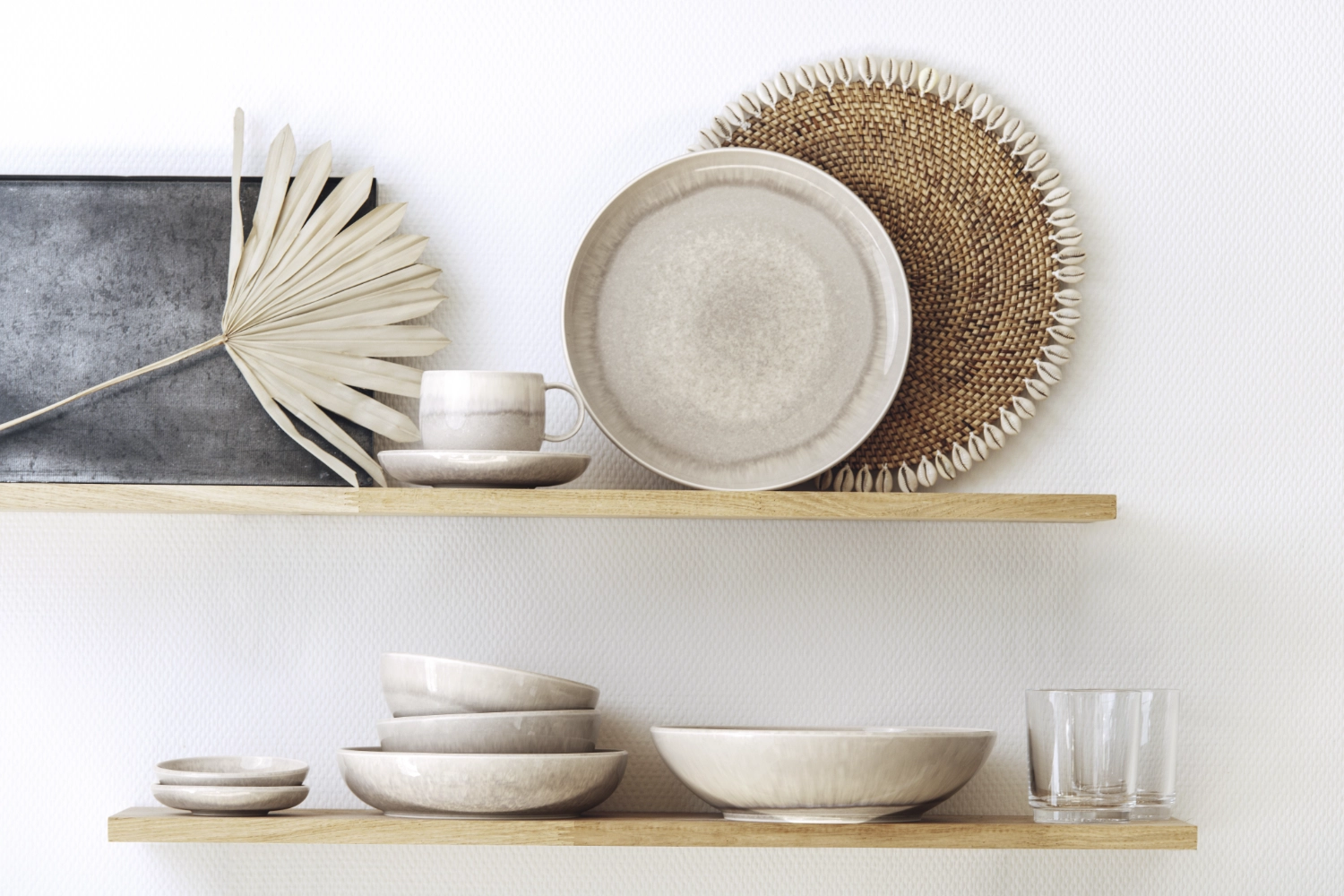Beiges Geschirr aus Keramik sowie Gläser und Dekoobjekte stehen auf zwei Holzregalen vor weißer Wand, natürlich und modern arrangiert.