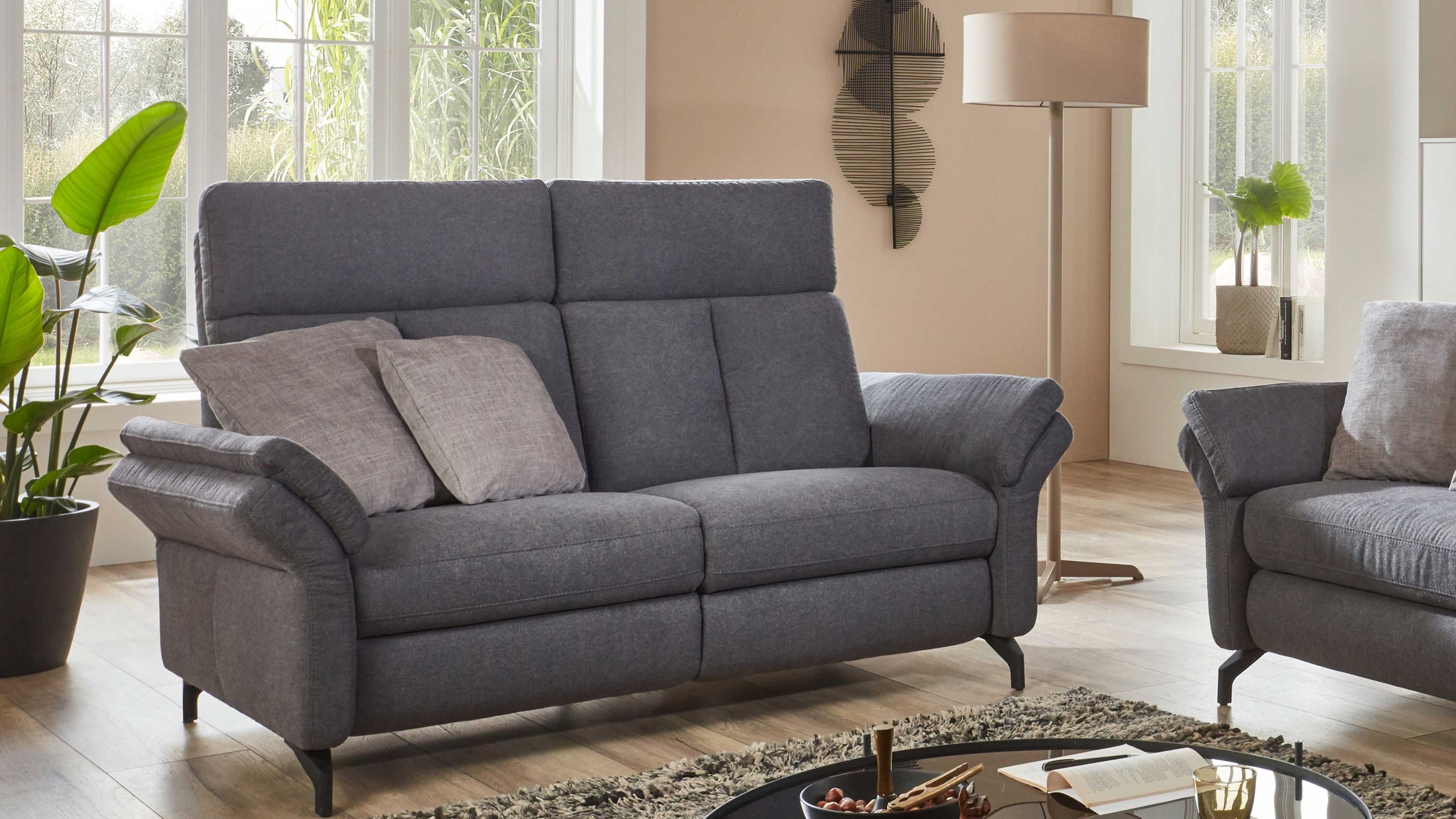 Zweisitziges Sofa mit anthrazitfarbenem Stoffbezug und zwei hellen Kissen in modernem Wohnzimmer
