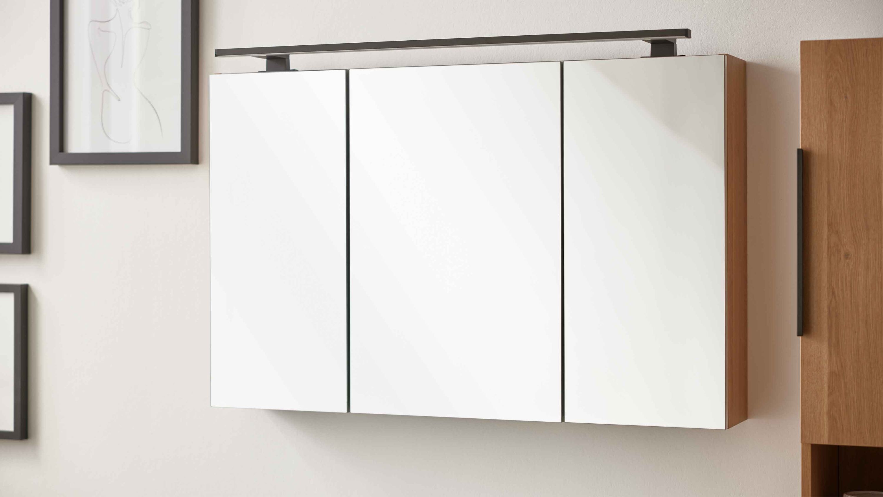 Spiegelschrank mit drei weißen Türen und braunen Seitenwänden an der Wand montiert