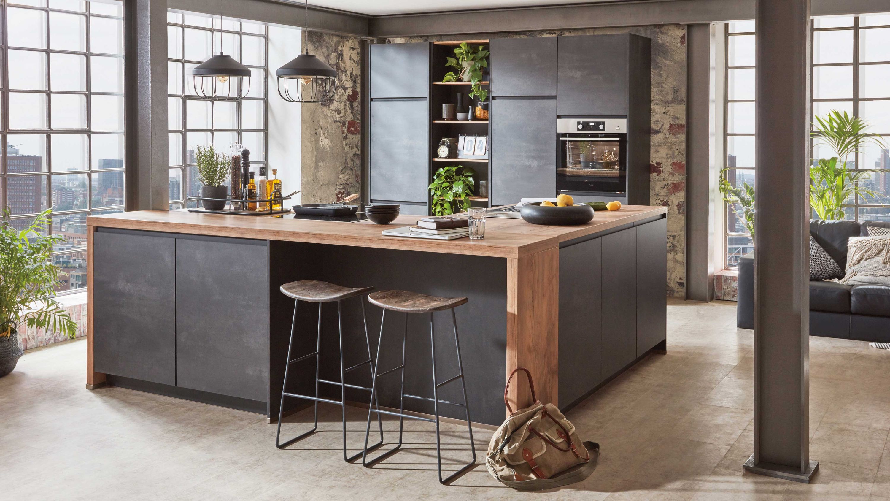 Offene Wohnküche mit Insel und industriellen Akzenten Kücheninsel mit Holzplatte dunkle Fronten Metallhocker Pendelleuchten Fensterlicht Regal Sofa im Hintergrund