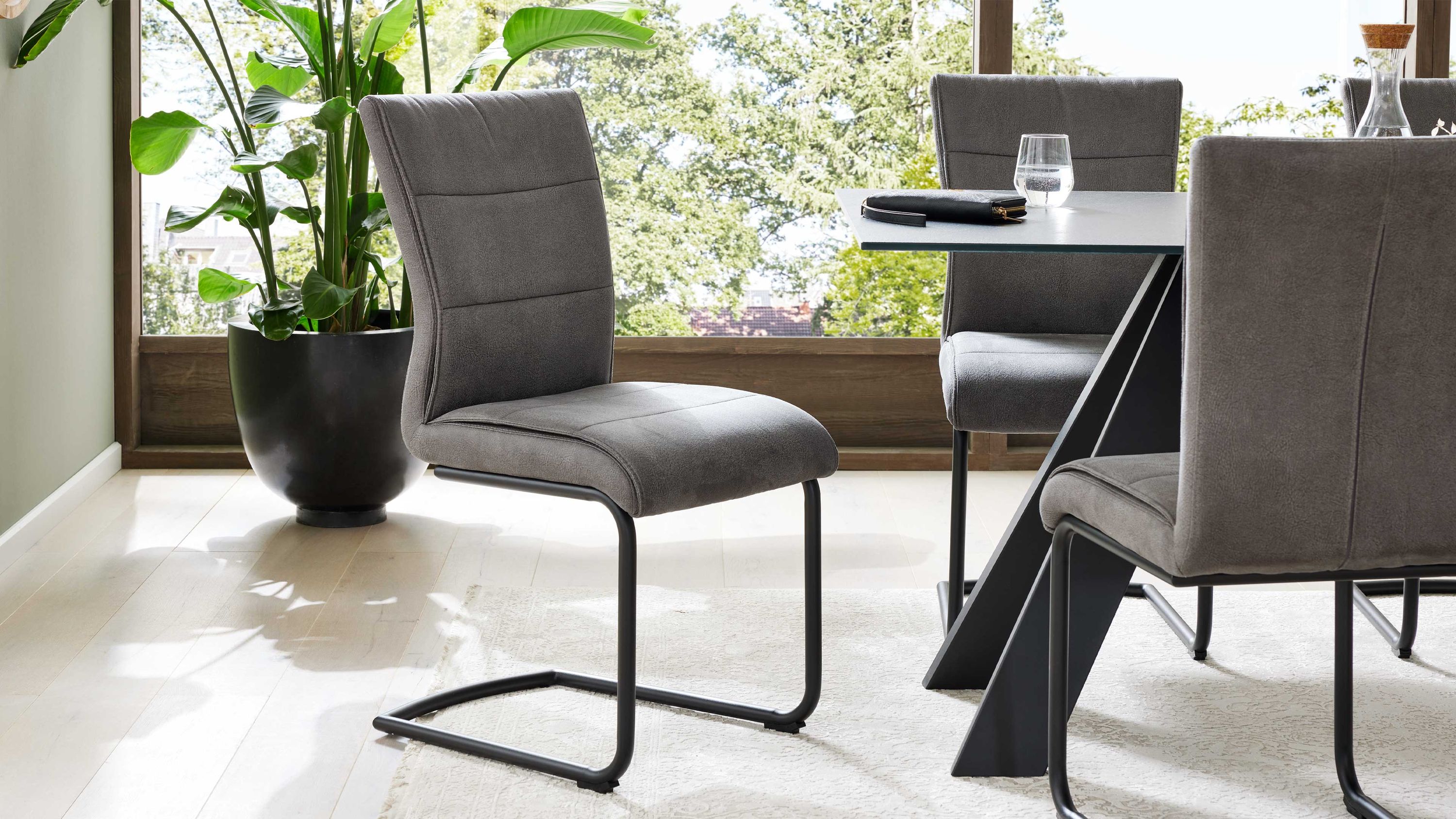 Schwingstuhl mit grauer Polsterung und schwarzem Metallgestell in modernem Esszimmer