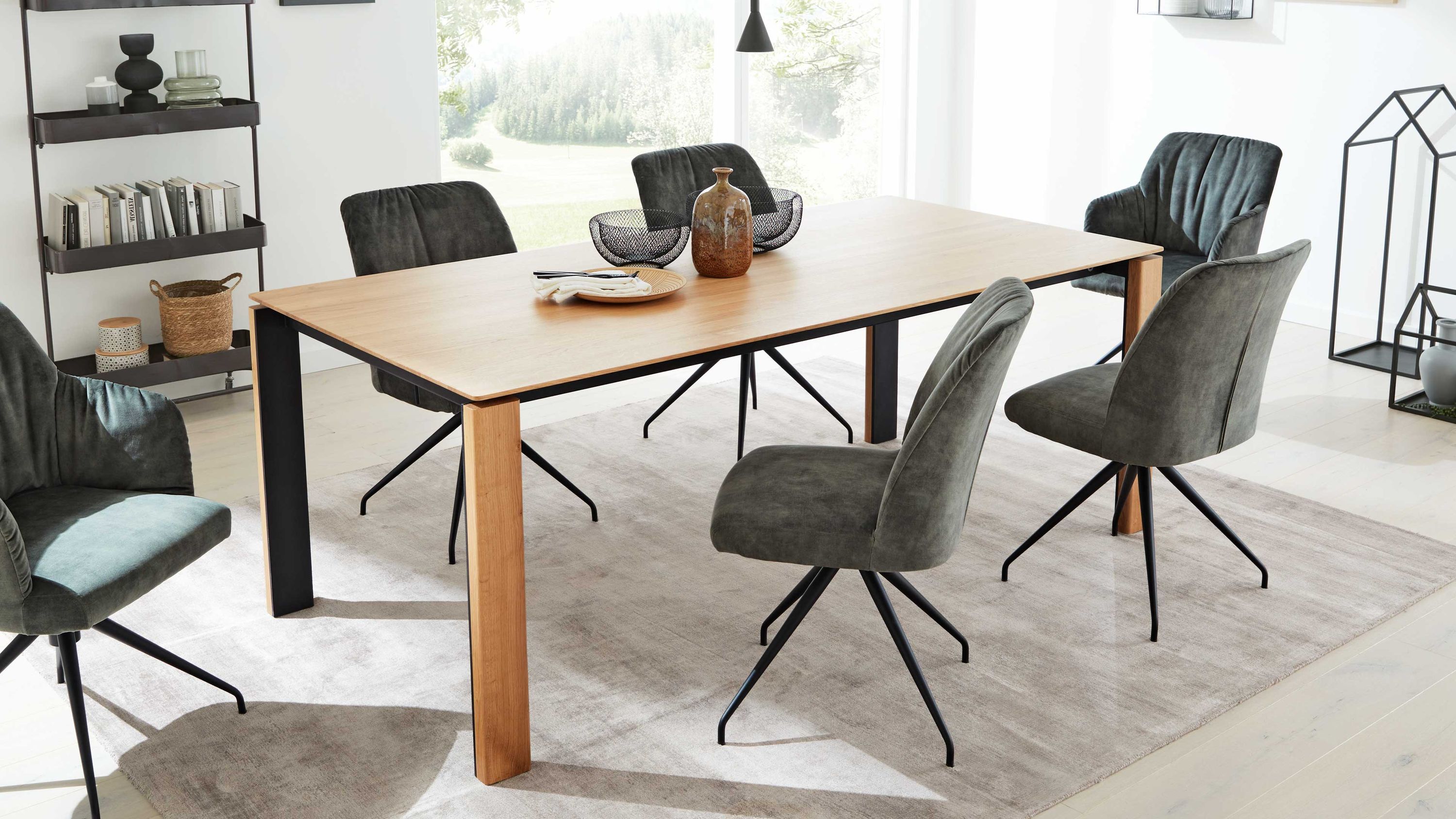 Rechteckiger Esstisch mit hellem Holz und schwarzen Metallbeinen umgeben von grauen Stühlen mit Metallbeinen