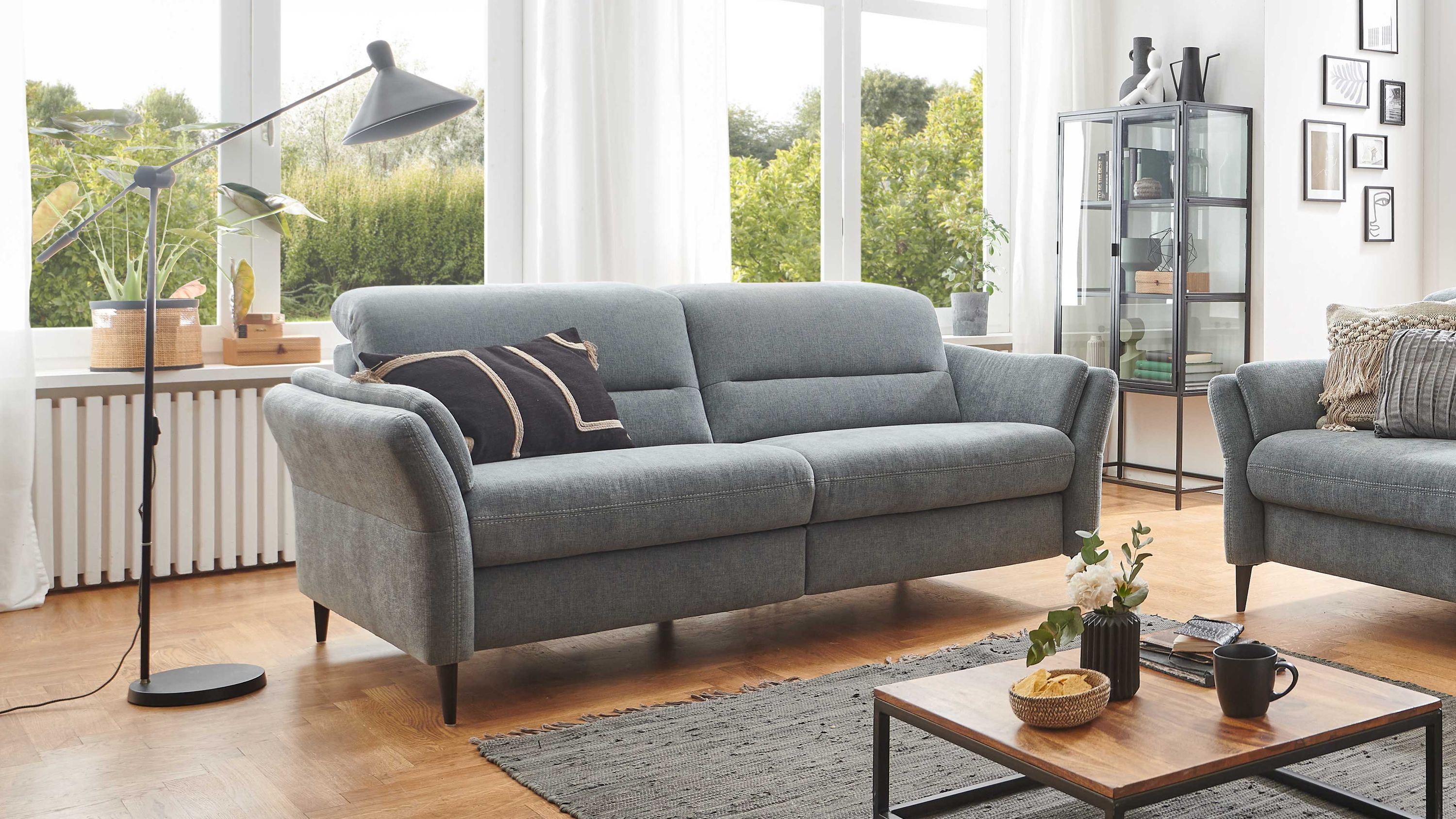 Zweisitziges Sofa mit stahlfarbenem Stoffbezug und schwarzen Metallfüßen in hellem Wohnzimmer