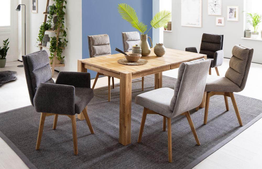 Sechs gepolsterte Schalenstühle mit Holzbeinen um Holztisch  in modernem Esszimmer mit blauer Wand und Pflanzen