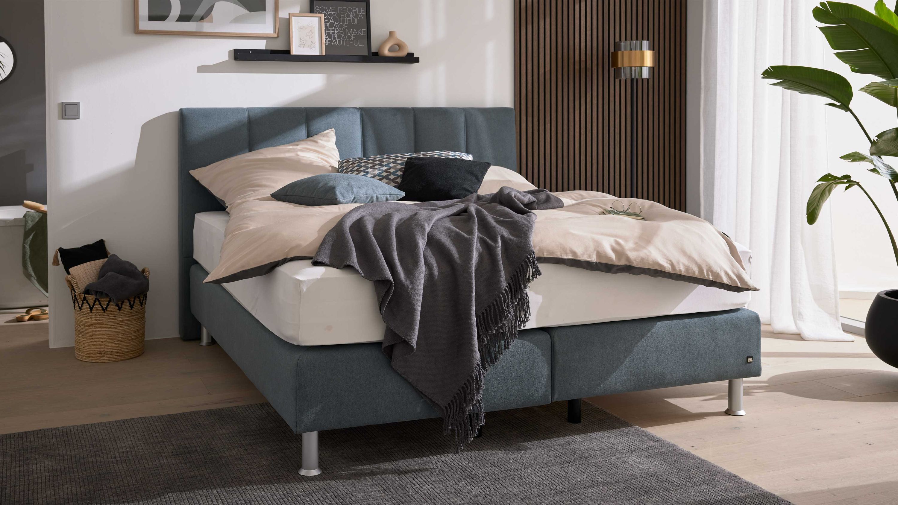 Boxspringbett mit gestepptem Kopfteil in Stahlfarbe Boxspringbett mit gestepptem Kopfteil und stahlfarbenem Bezug aus Mikrofaser mit Bettwäsche und Kissen
