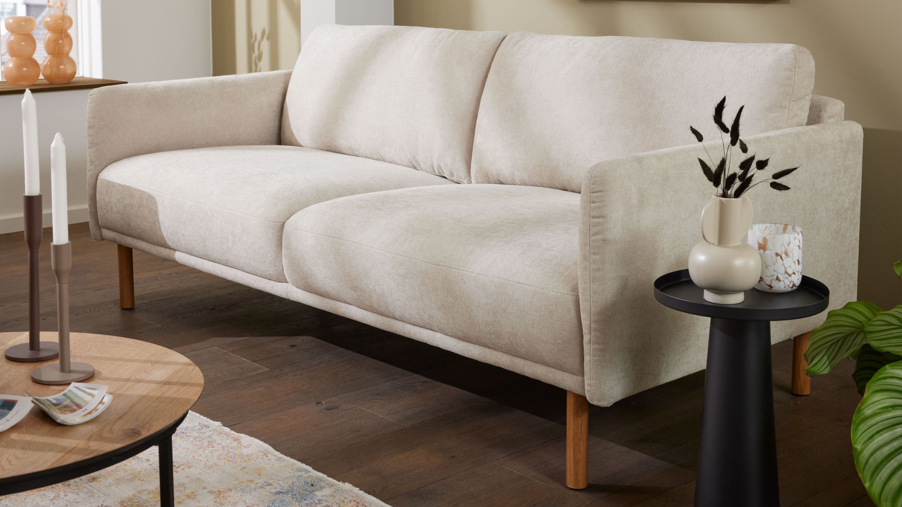 Zweisitziges Sofa mit naturfarbenem Bezug und Holzfüßen Zweisitziges Sofa mit naturfarbenem Bezug und Holzfüßen in modernem Wohnzimmer