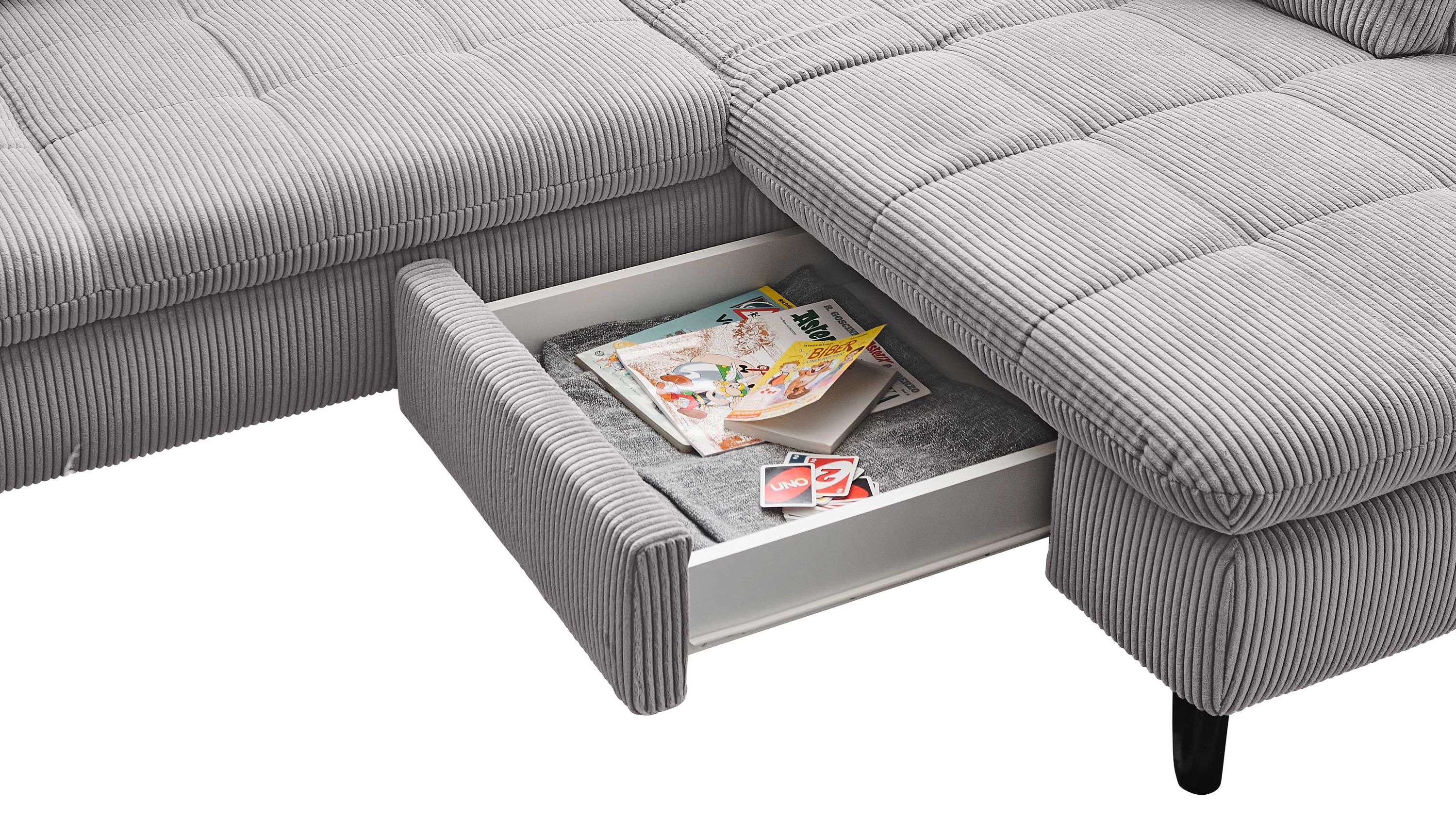 Geöffnete Stauraum-Schublade unter grauem Polstersofa mit geripptem Stoffbezug