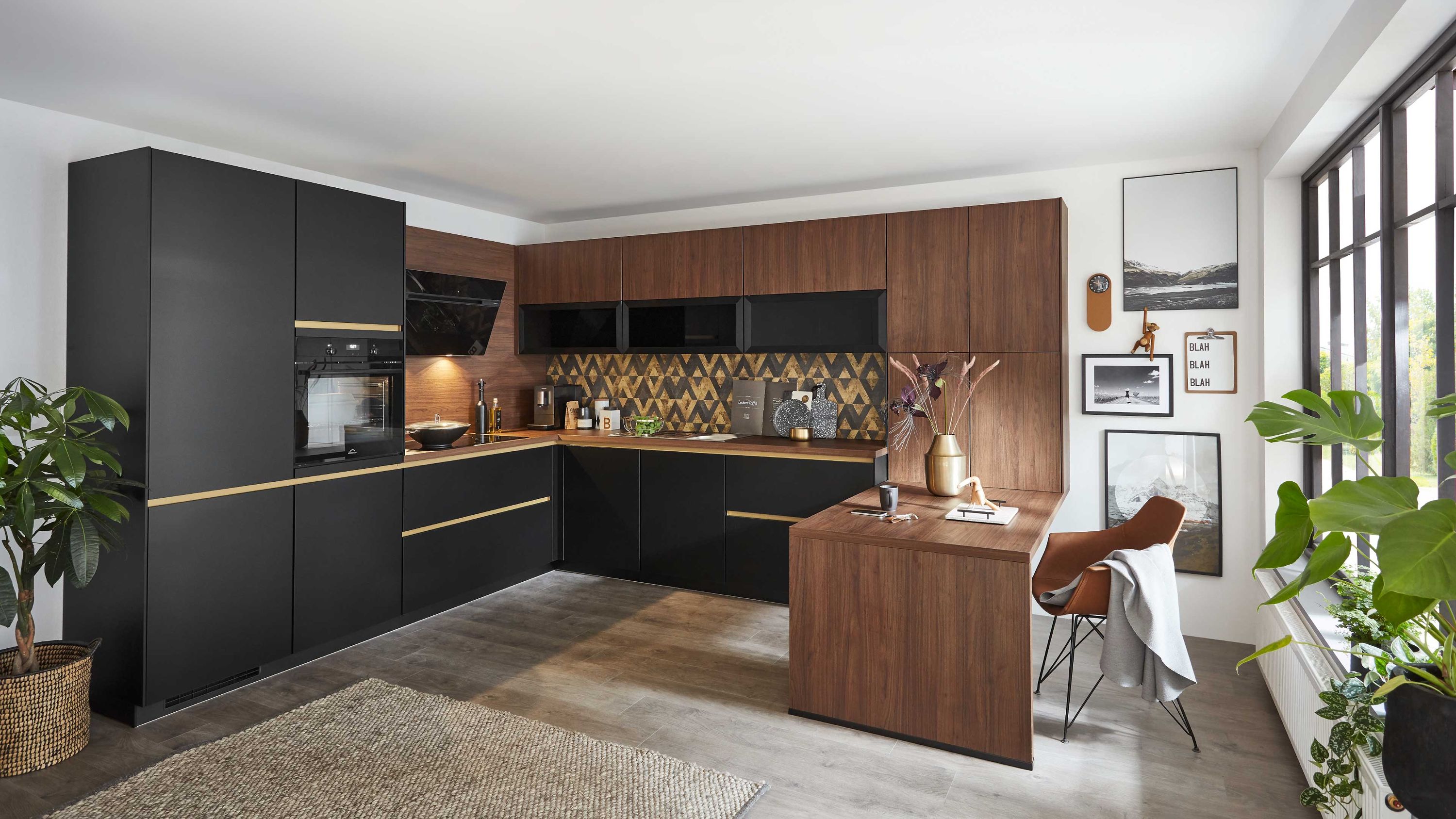 Winkelküche in Schwarz und Holzoptik mit goldenen Griffen gemusterter Rückwand und integrierter Sitztheke.