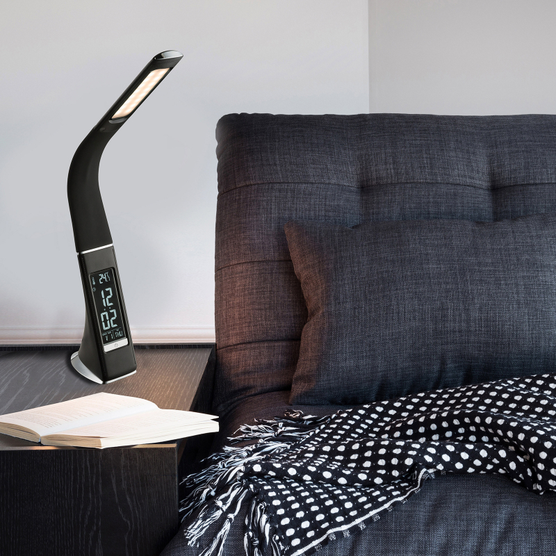 tischleuchte braun auf nachttisch neben bett mit buch Braune LED-Tischleuchte mit gebogenem Design auf Nachttisch neben Bett mit dunkler Bettwäsche