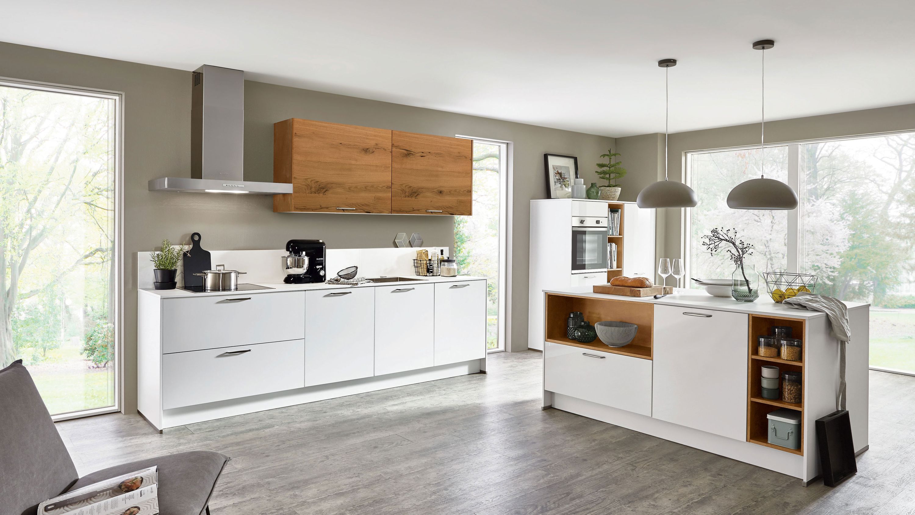 Küche mit weißen Fronten Holzdetails Insel mit Spüle Hängelampen Edelstahlgeräten und Fensterlicht