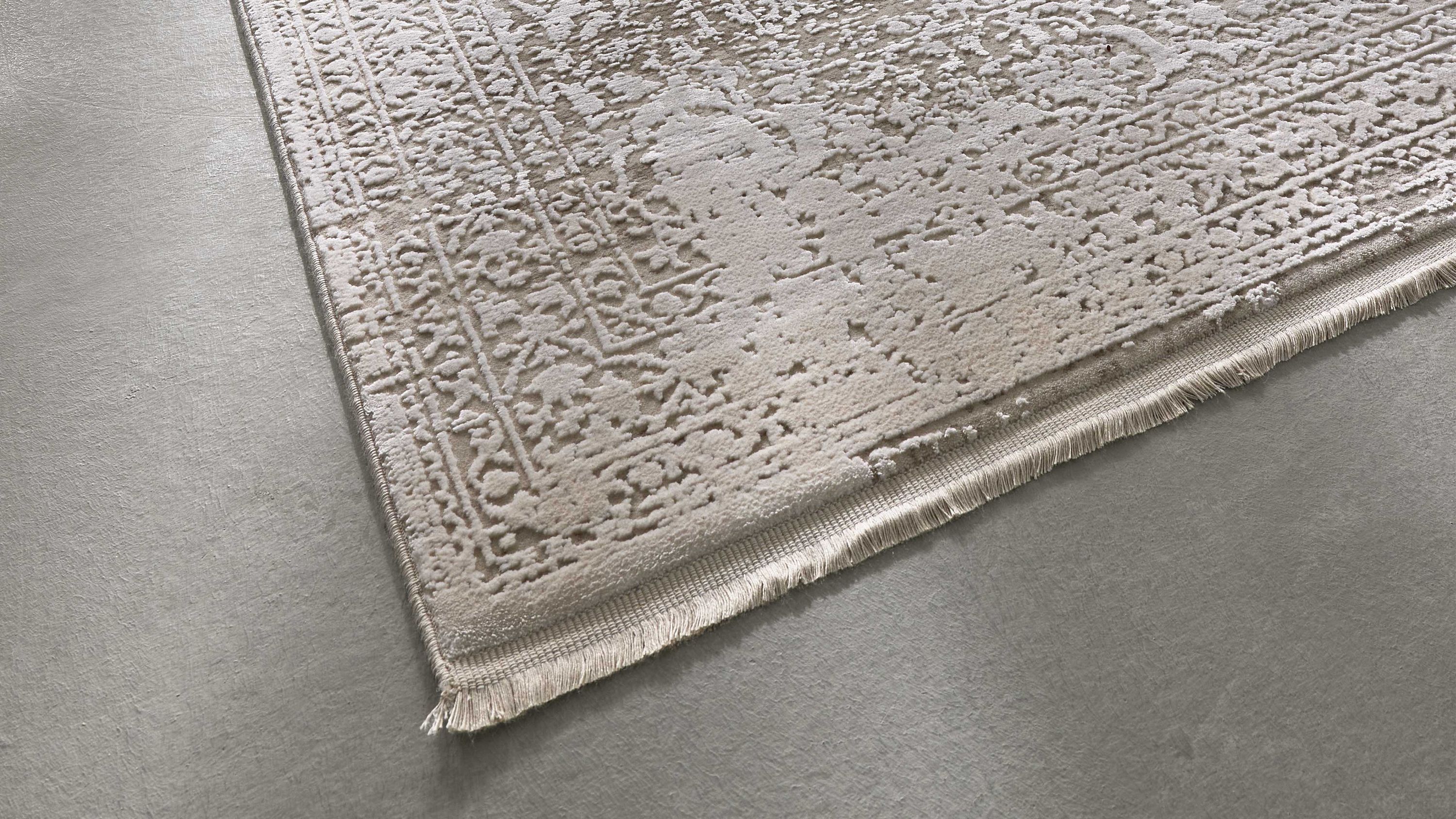 Eckiger Teppich mit floralen und geometrischen Mustern in silberner Farbe mit Fransen an der Kante