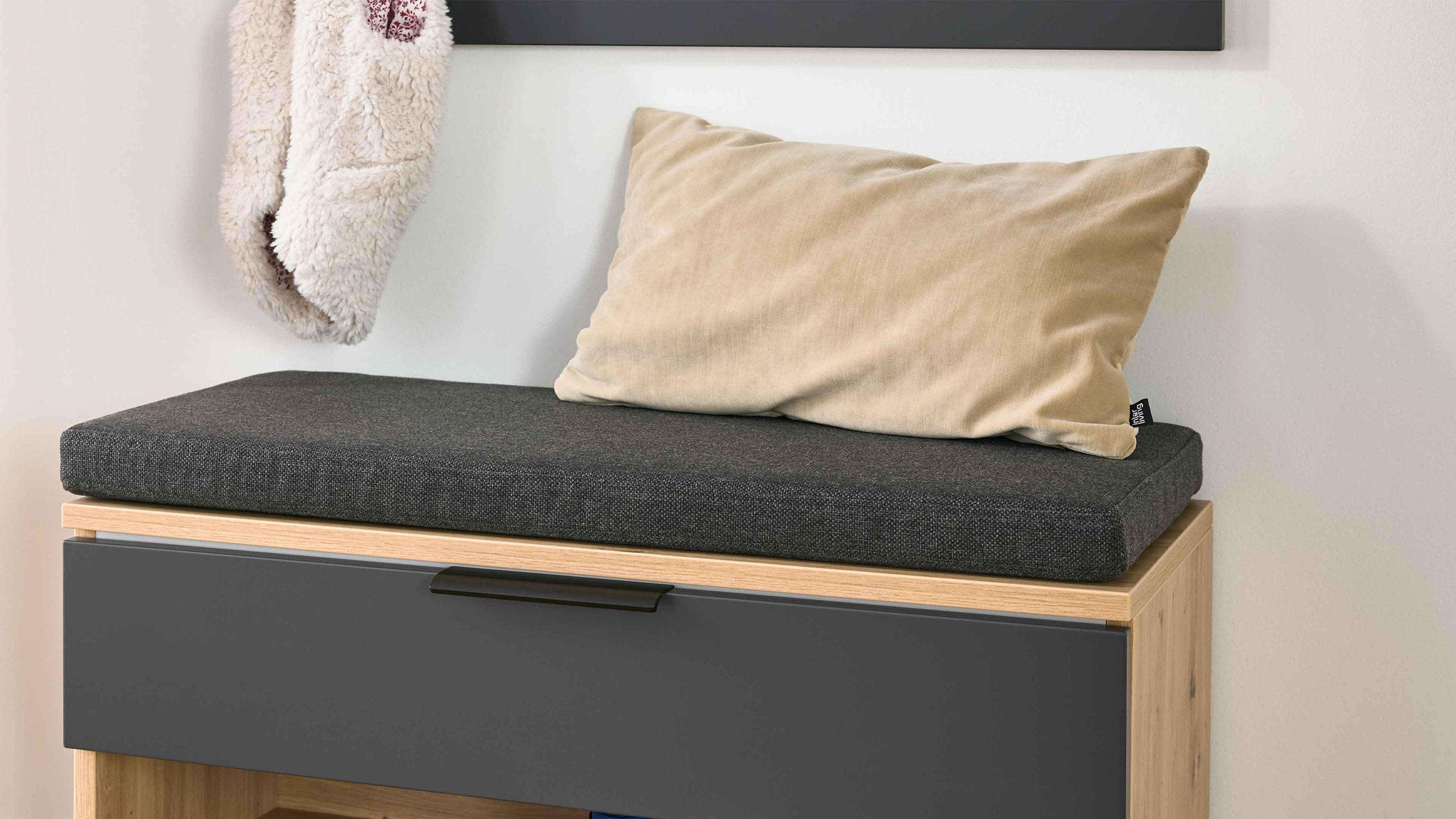 Sitzbank mit Sitzkissen und Kissen auf Holzgestell Sitzbank mit rechteckigem dunkelgrauem Sitzkissen und hellbeigem rechteckigem Kissen auf Holzgestell mit dunkler Front