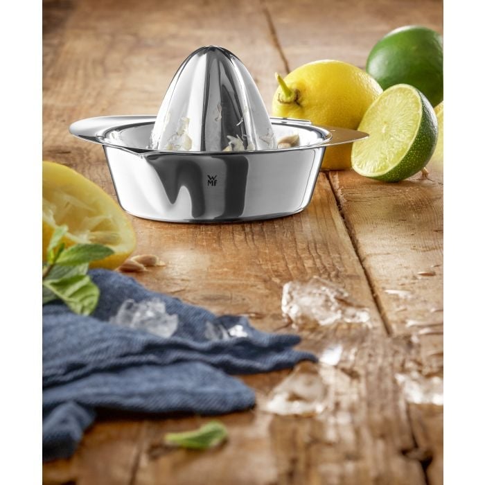 Edelstahl-Zitruspresse mit Zitrone, Limette, Eiswürfeln und Minze auf Holzuntergrund Silberne Zitronenpresse mit Zitronen & Limetten auf Holz blaues Tuch & Blätter unten links.