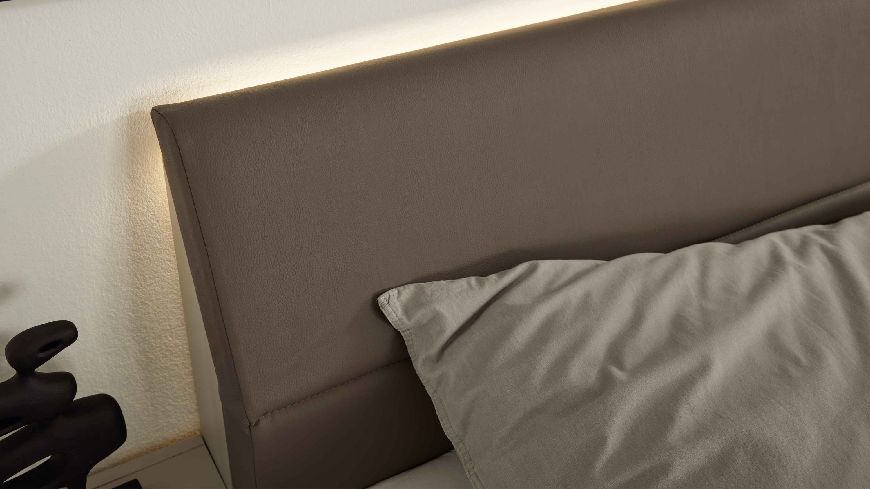 Braunes gepolstertes Kopfteil mit integrierter Beleuchtung an der Wand im Schlafzimmer