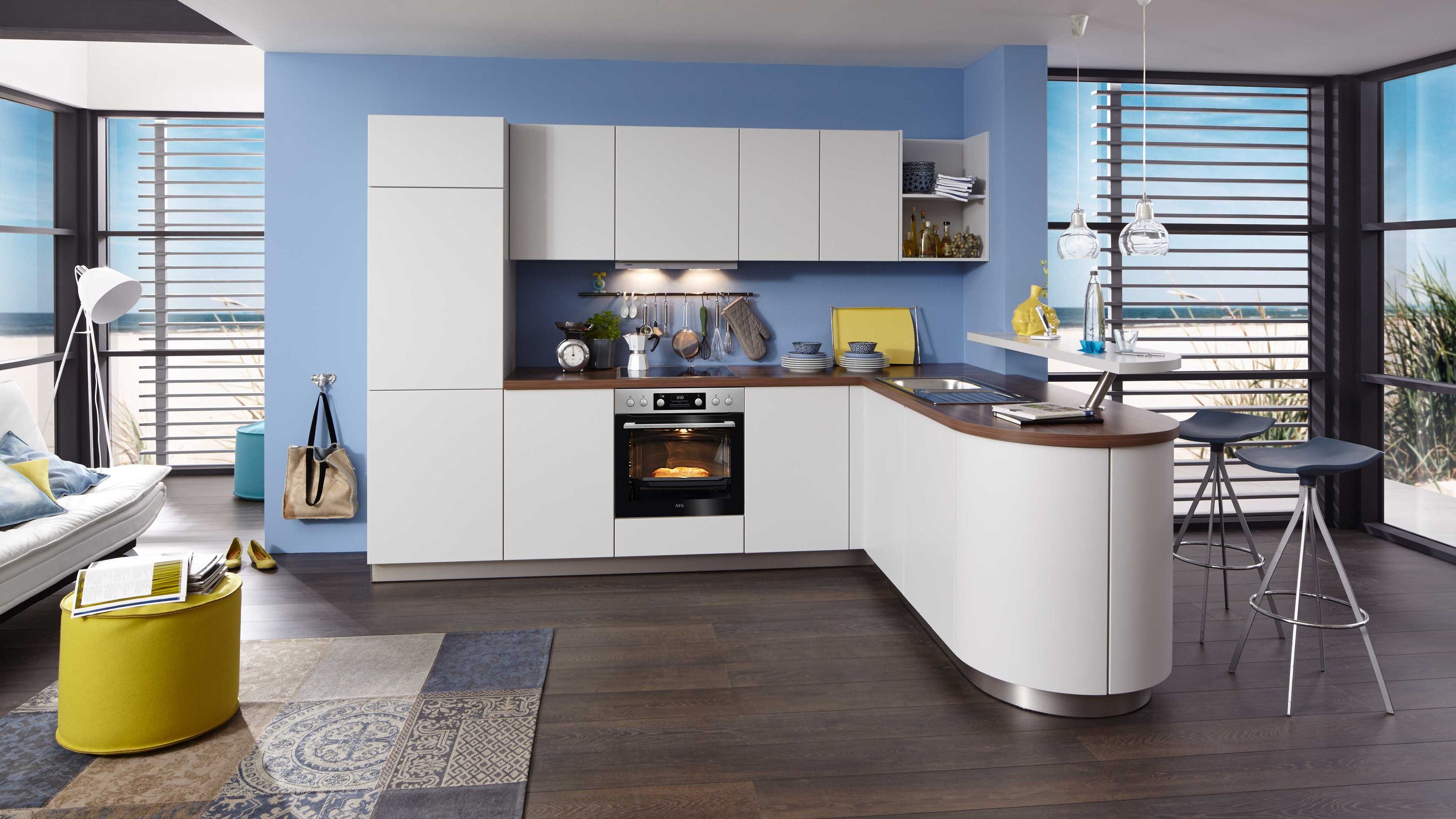 Weiße Küche mit runder Theke und blauer Wand. Weiße Küche mit abgerundeter Theke Holzarbeitsplatte Einbauofen und blauer Wandgestaltung im modernen Stil.